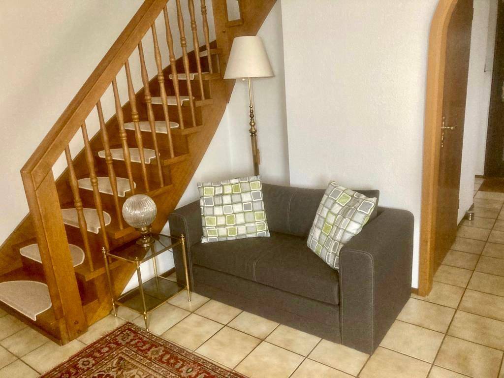 Detailansicht des Wohnzimmers mit Holztreppe, Sofa und Beistelltisch.