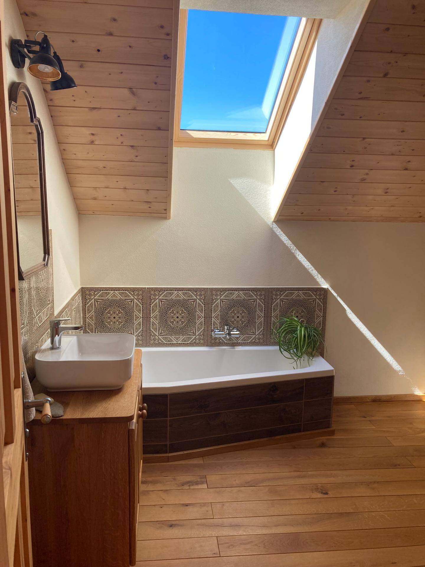 Badezimmer mit Badewanne, Waschtisch und Dachfenster für natürliches Licht.