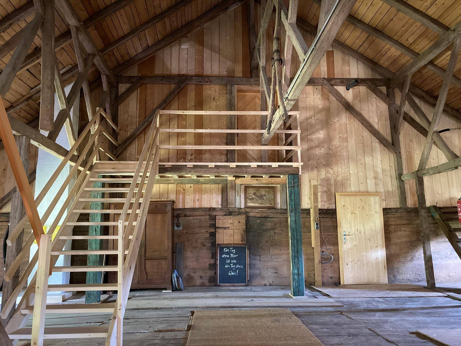 Großer Dachboden mit sichtbaren Holzbalken und einer neuen Holztreppe, bereit für den Ausbau.