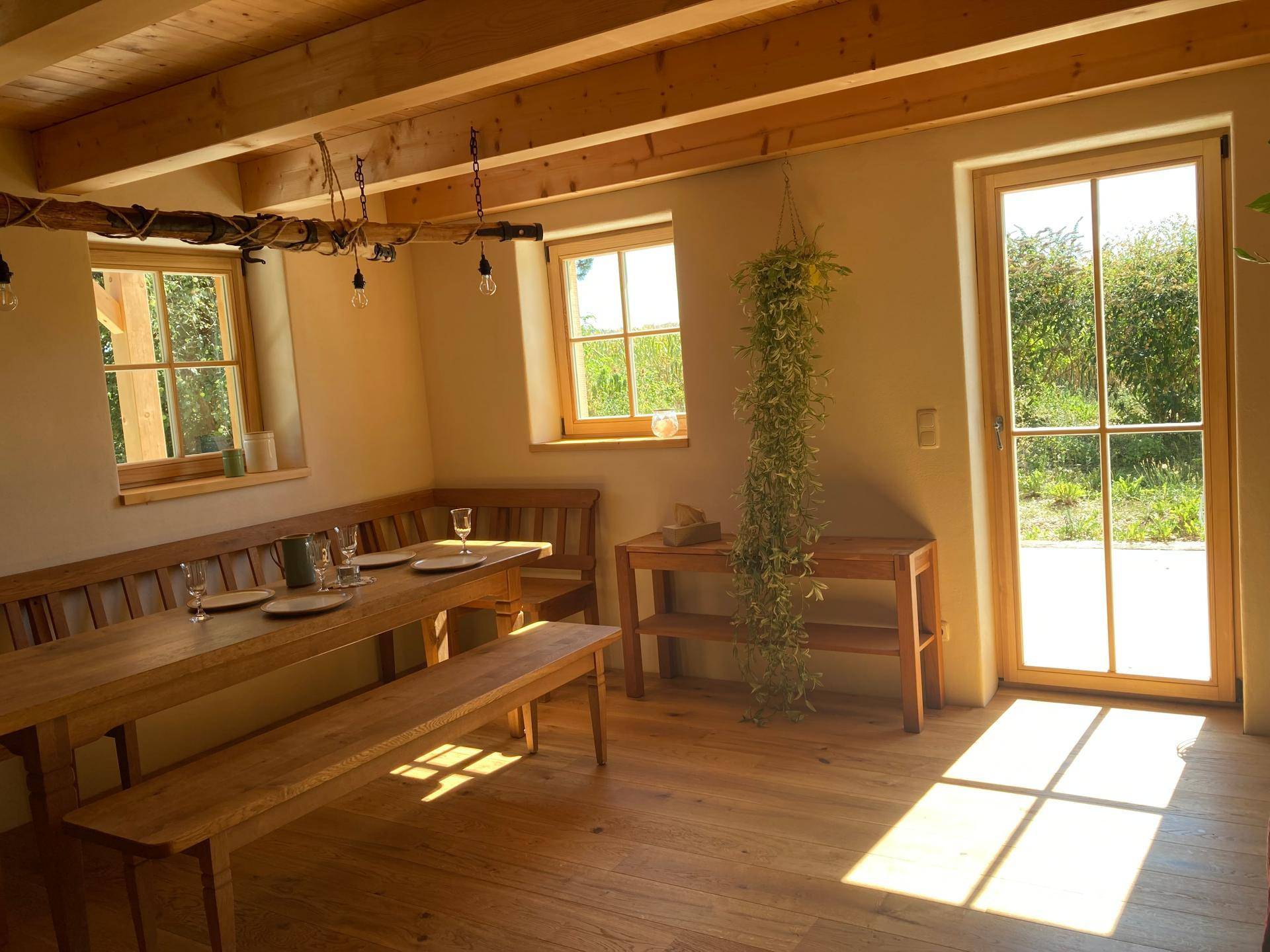 Gemütlicher Essbereich mit Holzbänken, großem Tisch und Zugang zur Terrasse oder Garten.