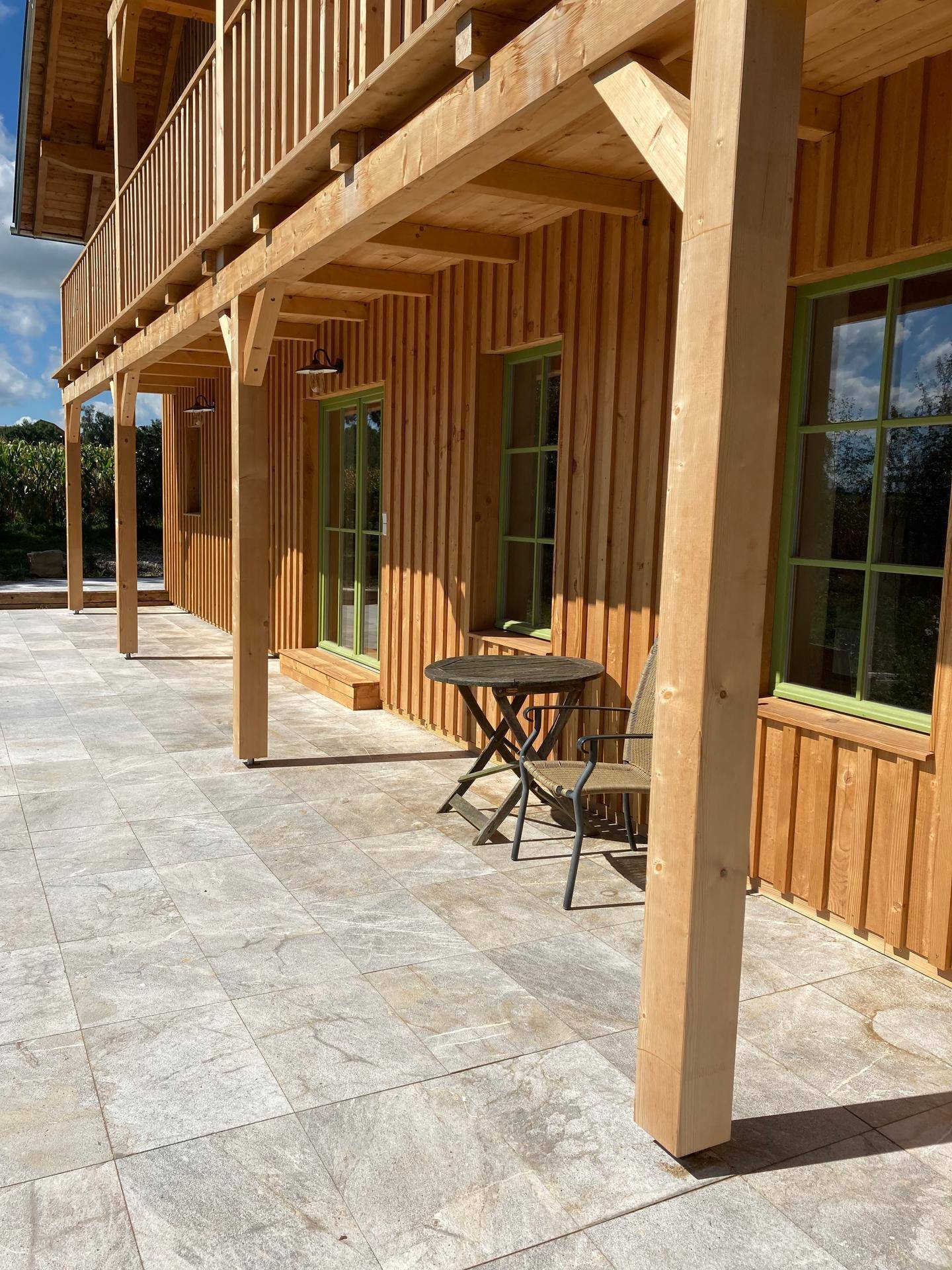 Geräumige überdachte Terrasse mit hellem Fliesenboden und Holzbalken, perfekt für Mahlzeiten im Freien.