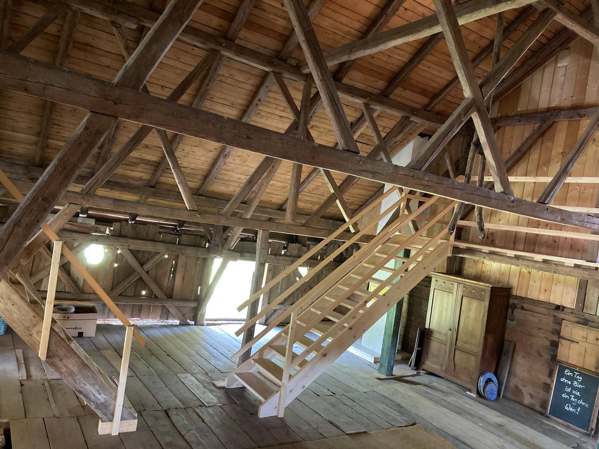 Geräumiger Dachboden mit Holztreppe und einer robusten Holzkonstruktion unter dem Dach.