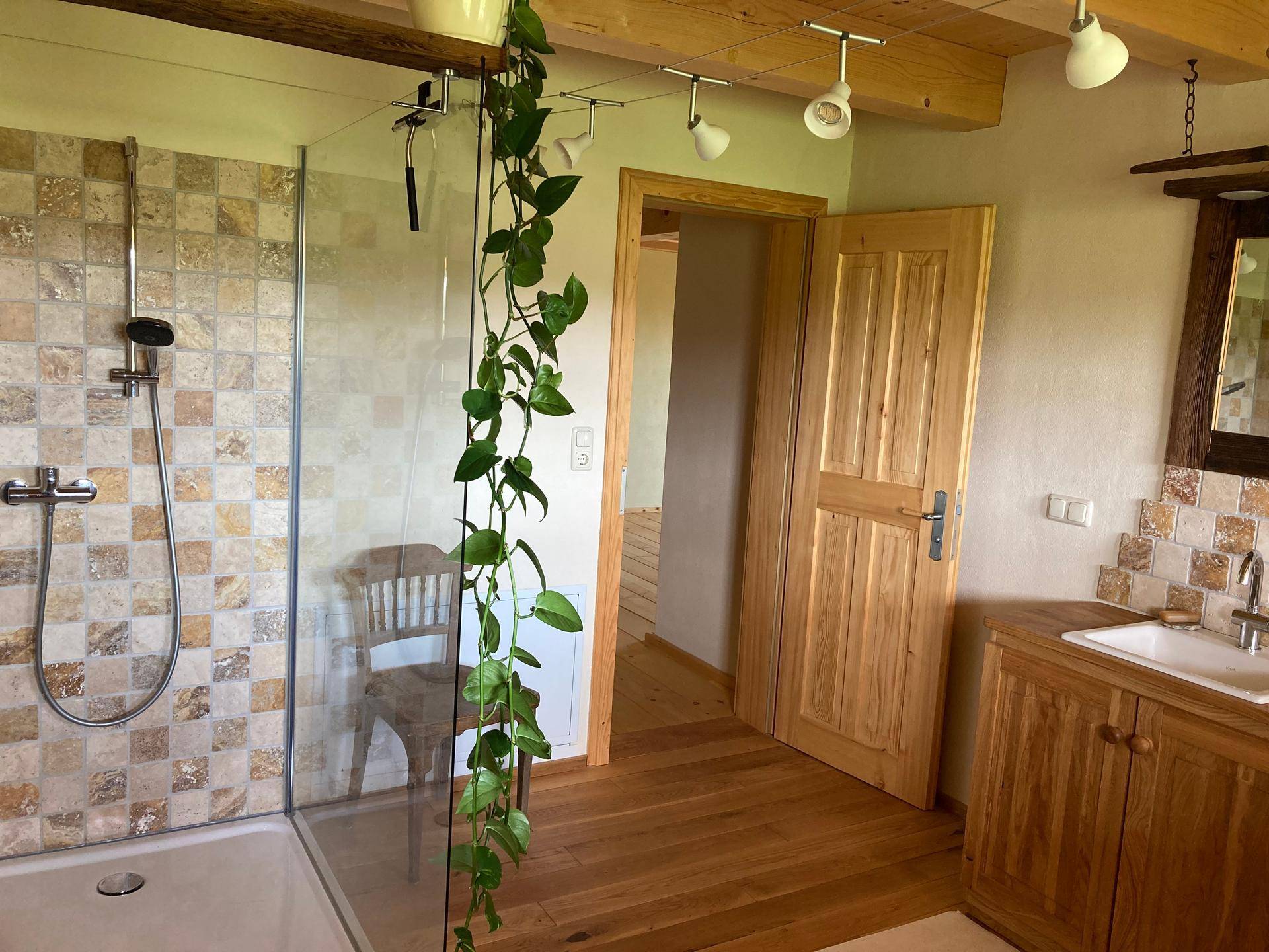 Badezimmer mit begehbarer Dusche, Holzwaschtisch und rustikalen Fliesen.