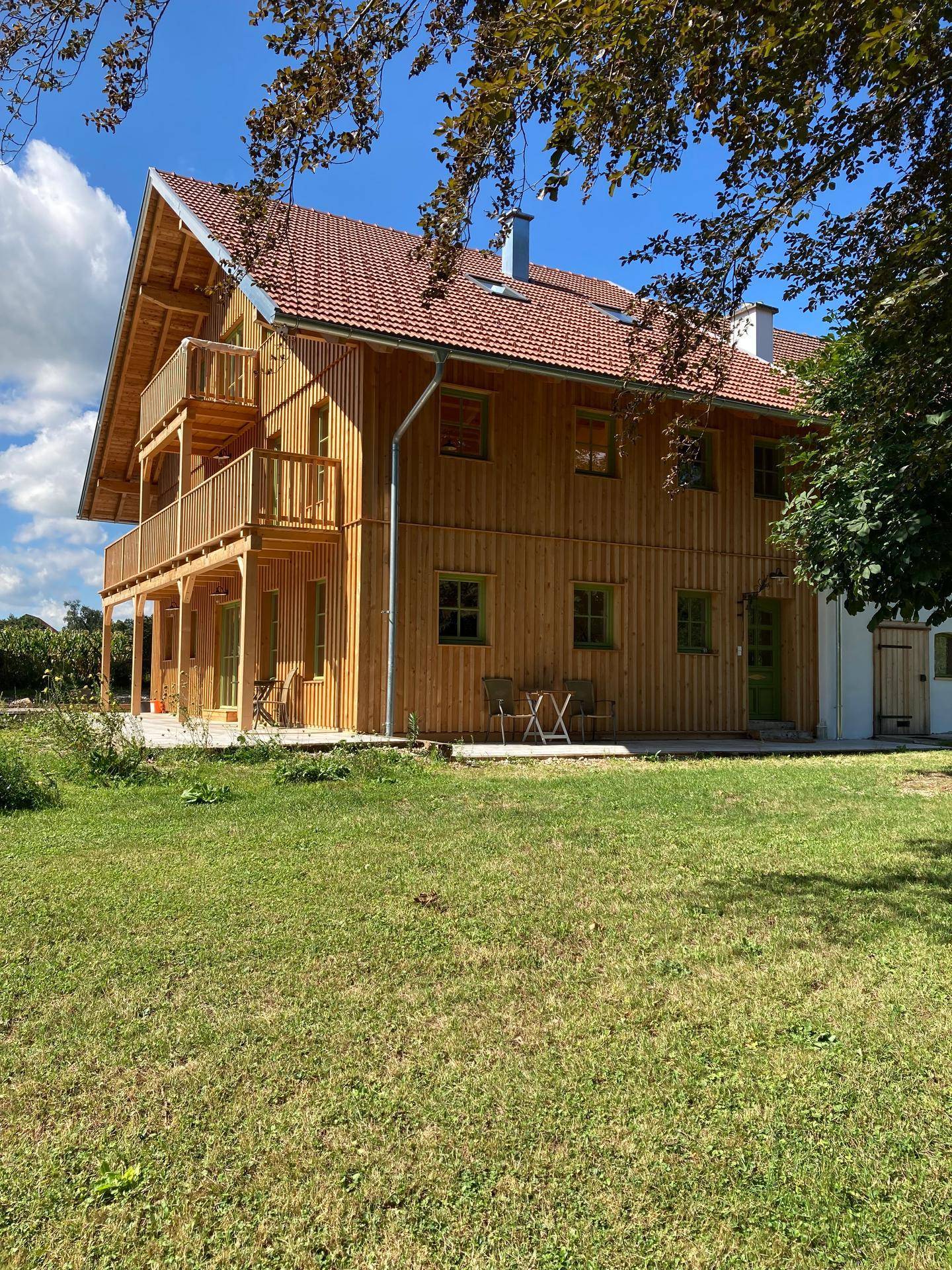 Idyllisches Holzhaus mit mehreren Balkonen und einem weitläufigen grünen Gartenbereich.