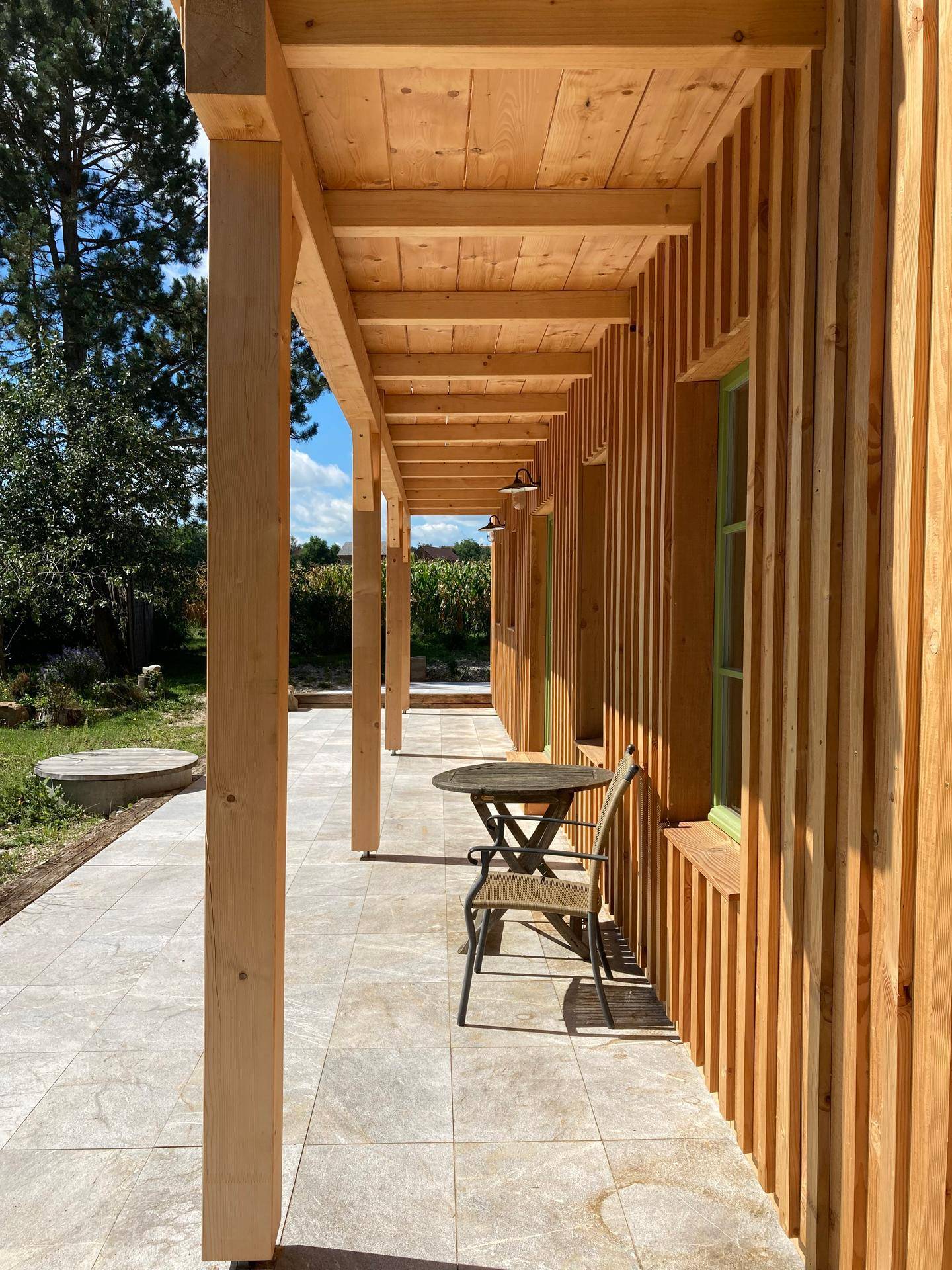Überdachte Terrasse mit Fliesenboden und Holzsäulen, ideal für entspannte Stunden im Freien.