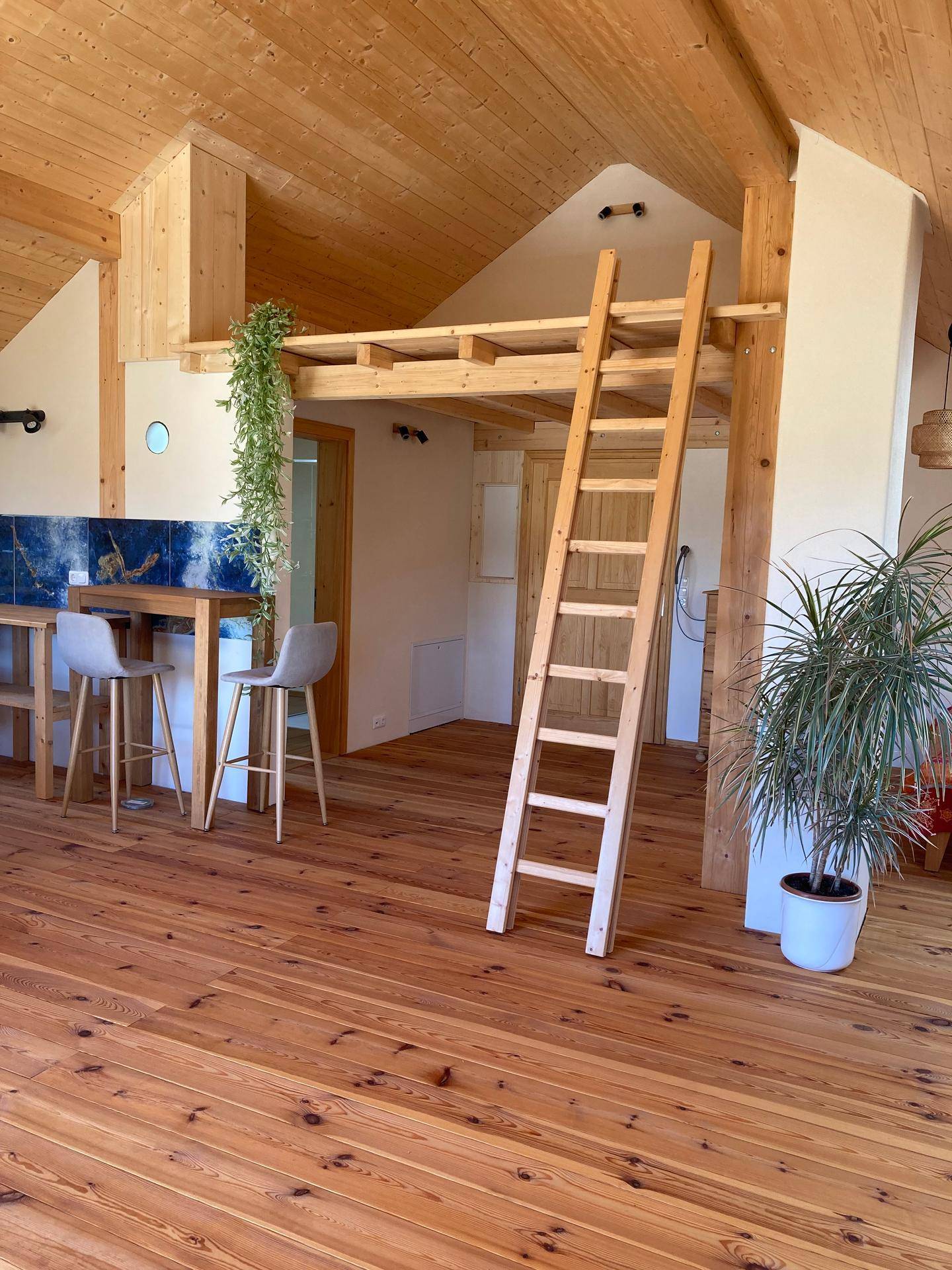 Kleine Küchenzeile mit Holzarbeitsplatte, Barhockern und Leiter zum Hochbett.