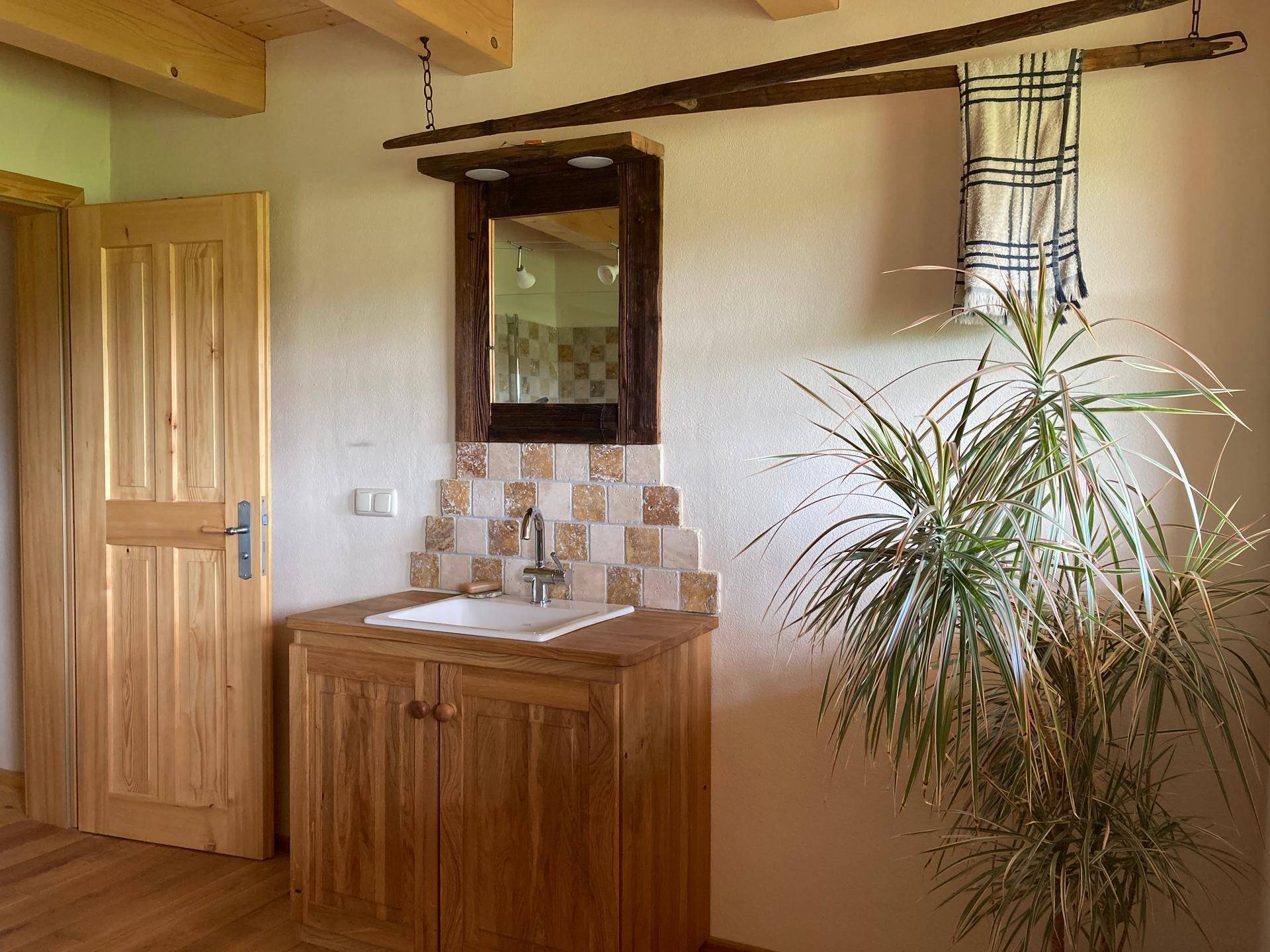 Badezimmer mit Holzwaschtisch, Spiegel und rustikalen Fliesen.