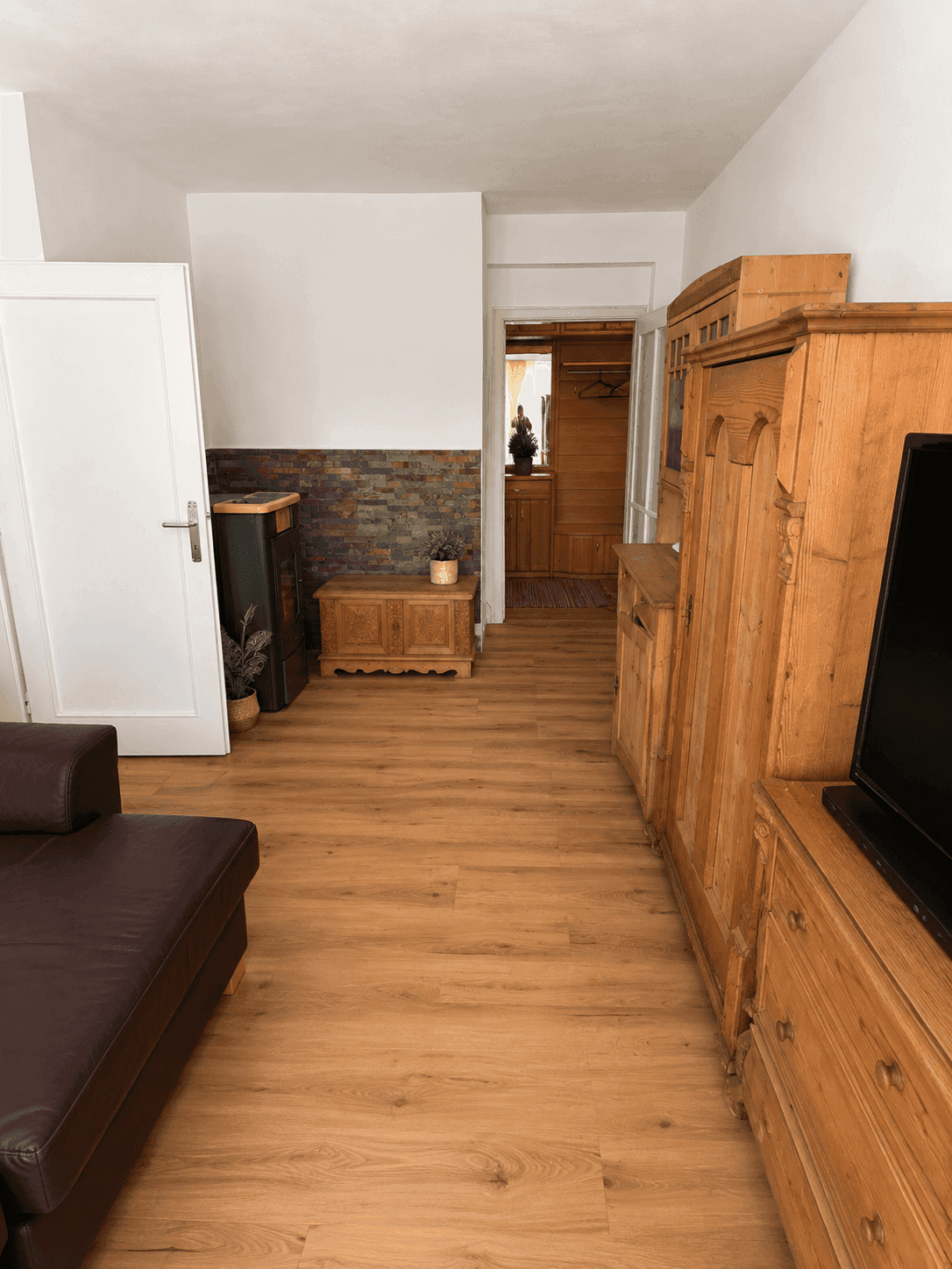 Gemütlicher Flur mit Ledersofa, rustikalen Holzmöbeln und einer Steinwandakzent.