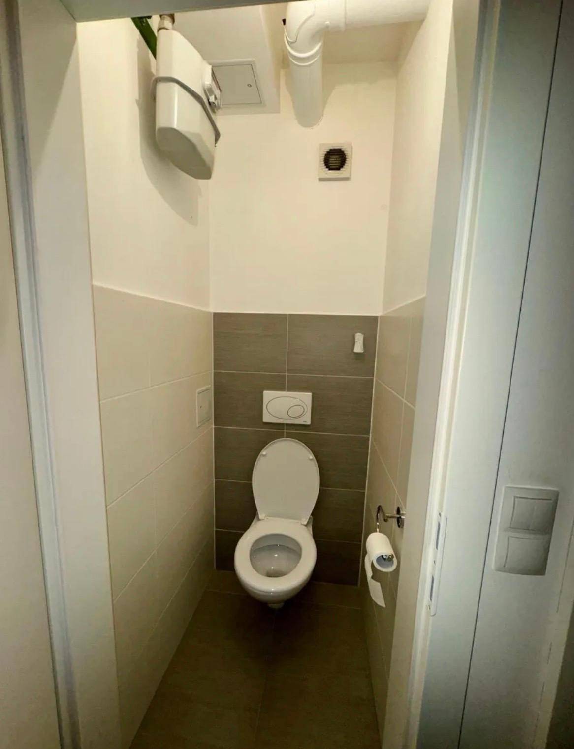 Modernes Gäste-WC mit Wand-WC und grauen Fliesen.