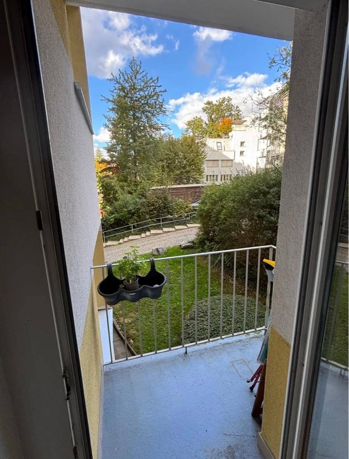 Kleiner Balkon mit Blick auf Bäume und den Innenhof.