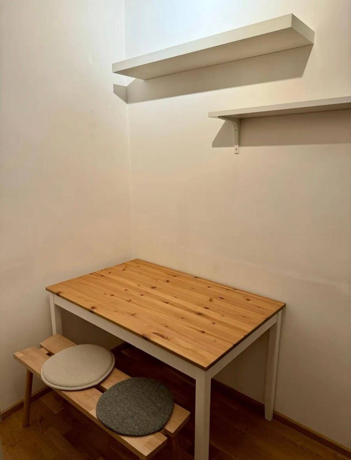 Gemütliche Essecke in der Küche mit Holztisch und Wandregalen.
