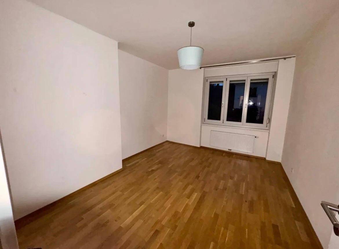 Leeres Zimmer mit Holzboden und Fenster, bereit zur individuellen Gestaltung.