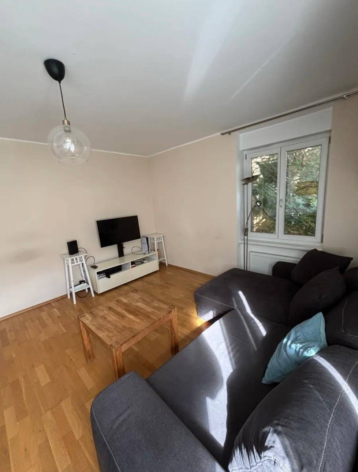 Gemütliches Wohnzimmer mit Sofa, Couchtisch und Fernseher.
