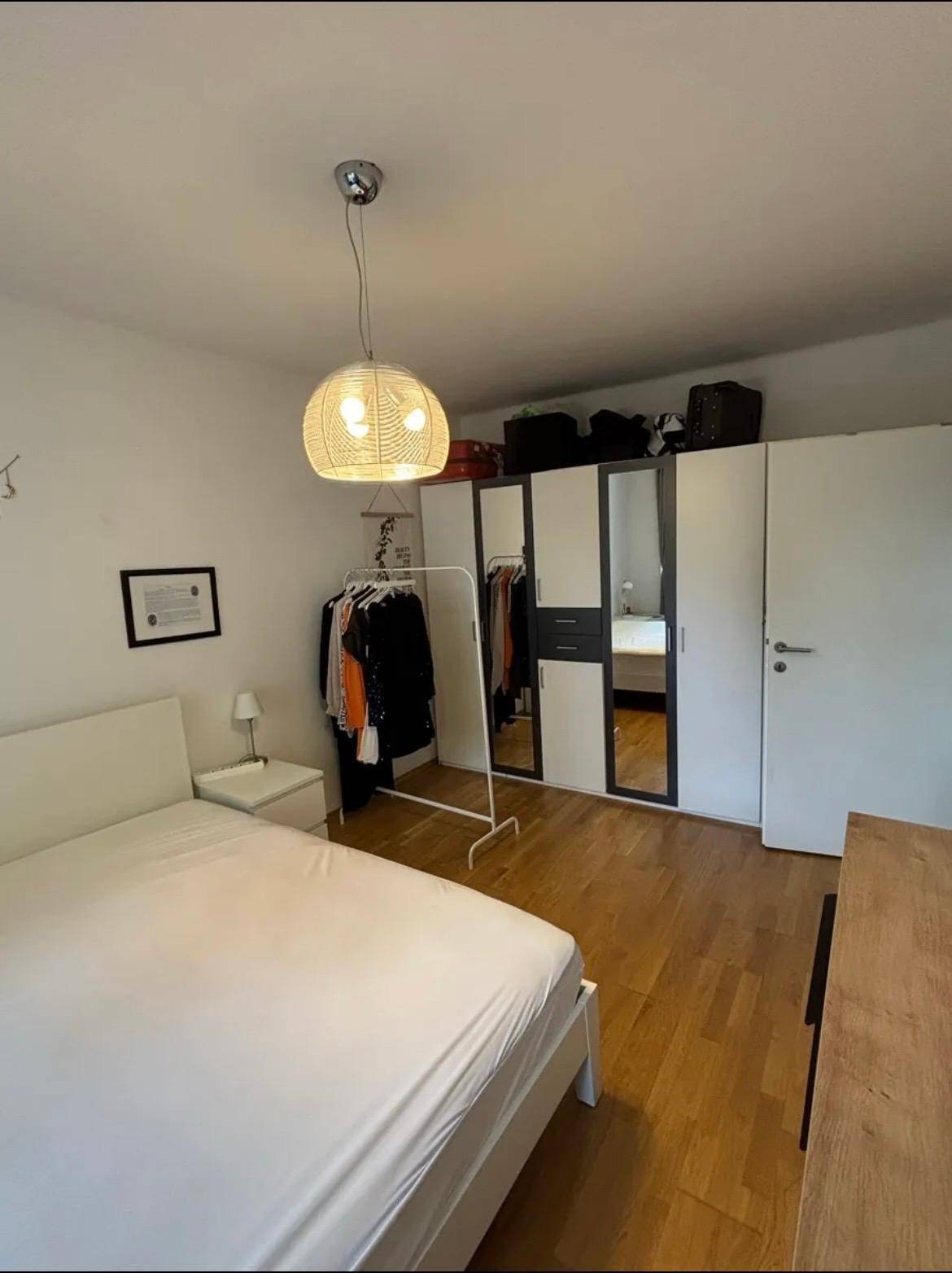 Helles Schlafzimmer mit Holzboden, Kleiderschrank und modernem Bett.