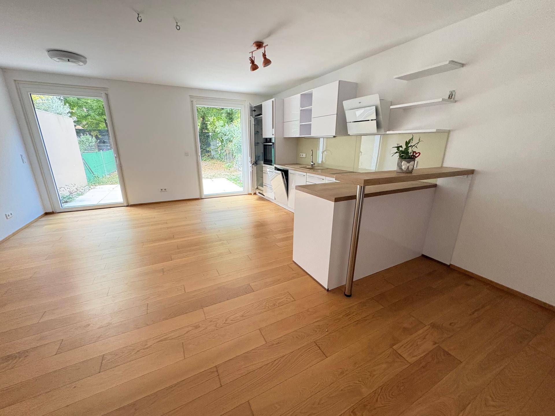 Moderne offene Küche mit Holzboden, Bartheke und direktem Zugang zum Gartenbereich.