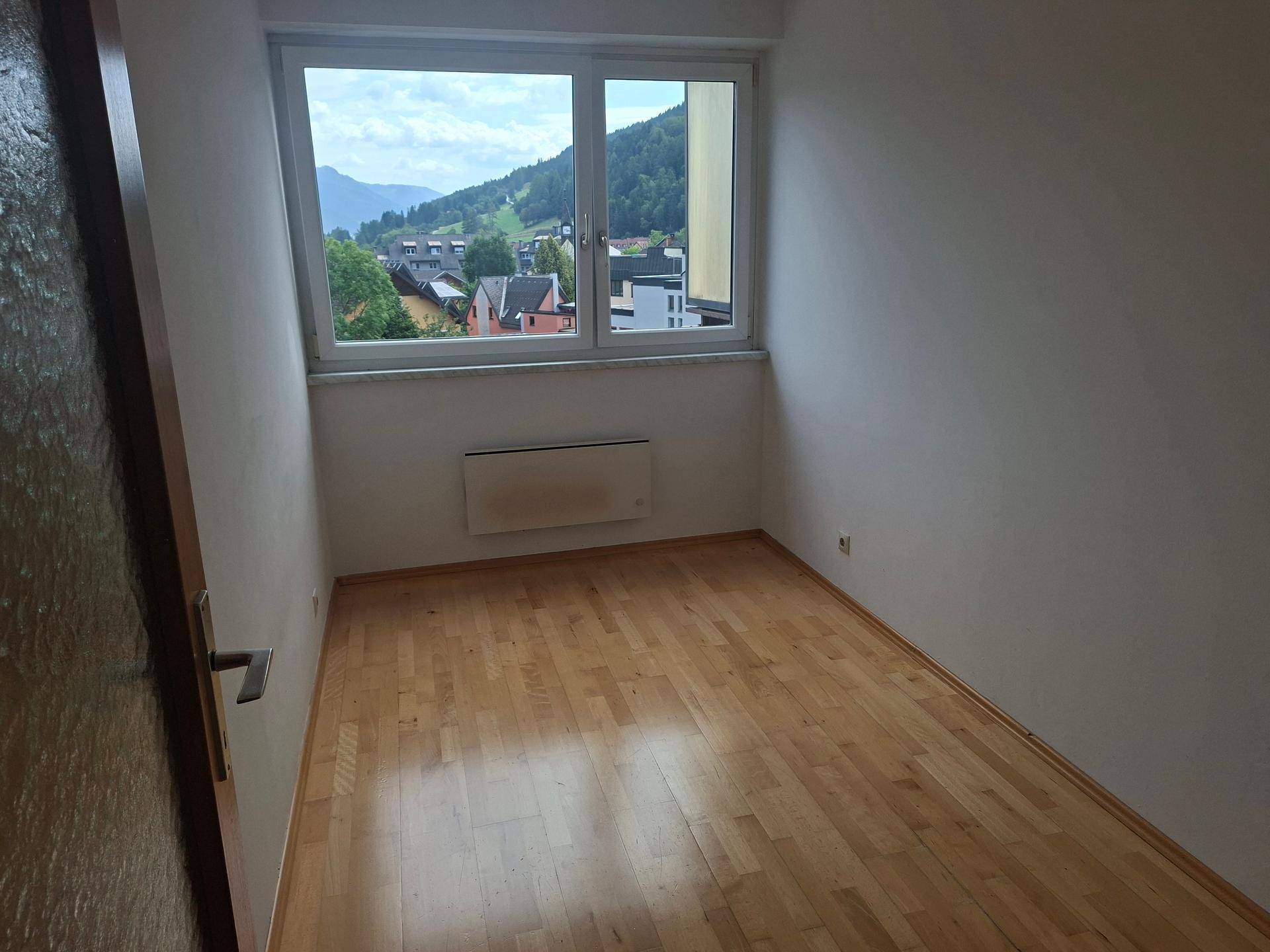 Kleines Zimmer mit Holzboden und Fenster, das einen Blick auf die umliegende Landschaft bietet.