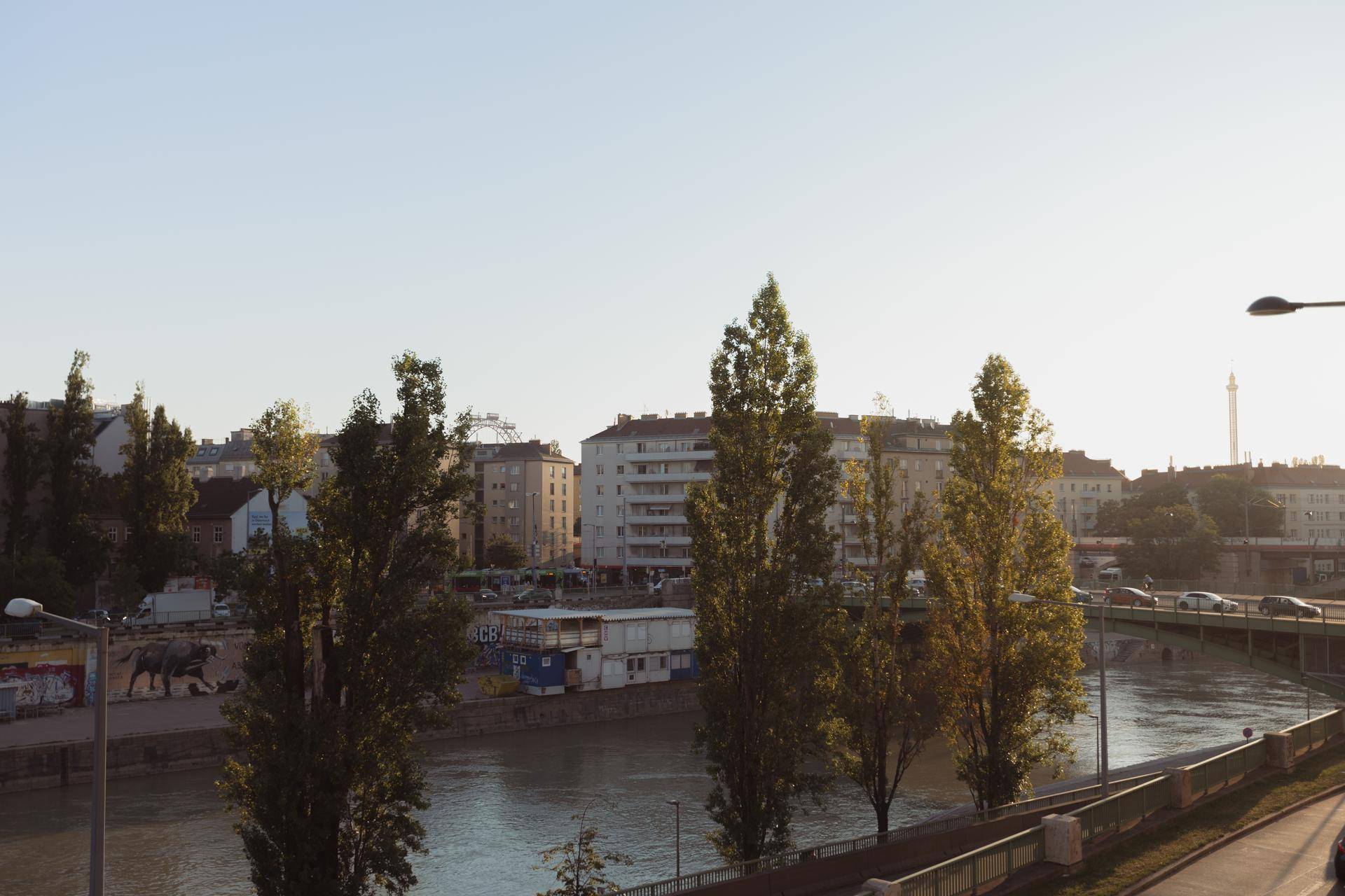 Panoramablick auf die Stadt mit Fluss, Gebäuden und Bäumen unter blauem Himmel.