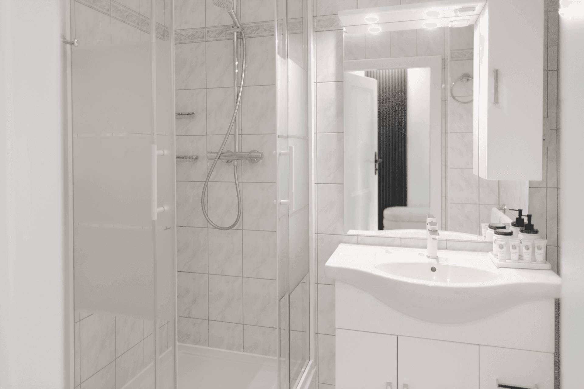 Helles Badezimmer mit Duschkabine, Waschbecken und Spiegelschrank.