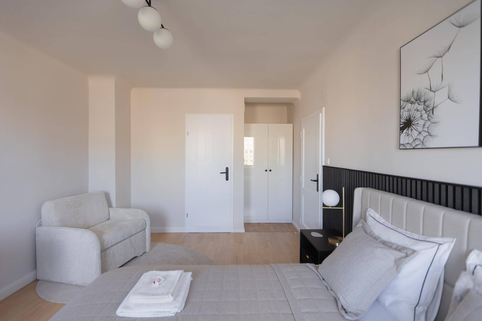 Helles Schlafzimmer mit bequemen Sessel und Zugang zu einem Kleiderschrank.