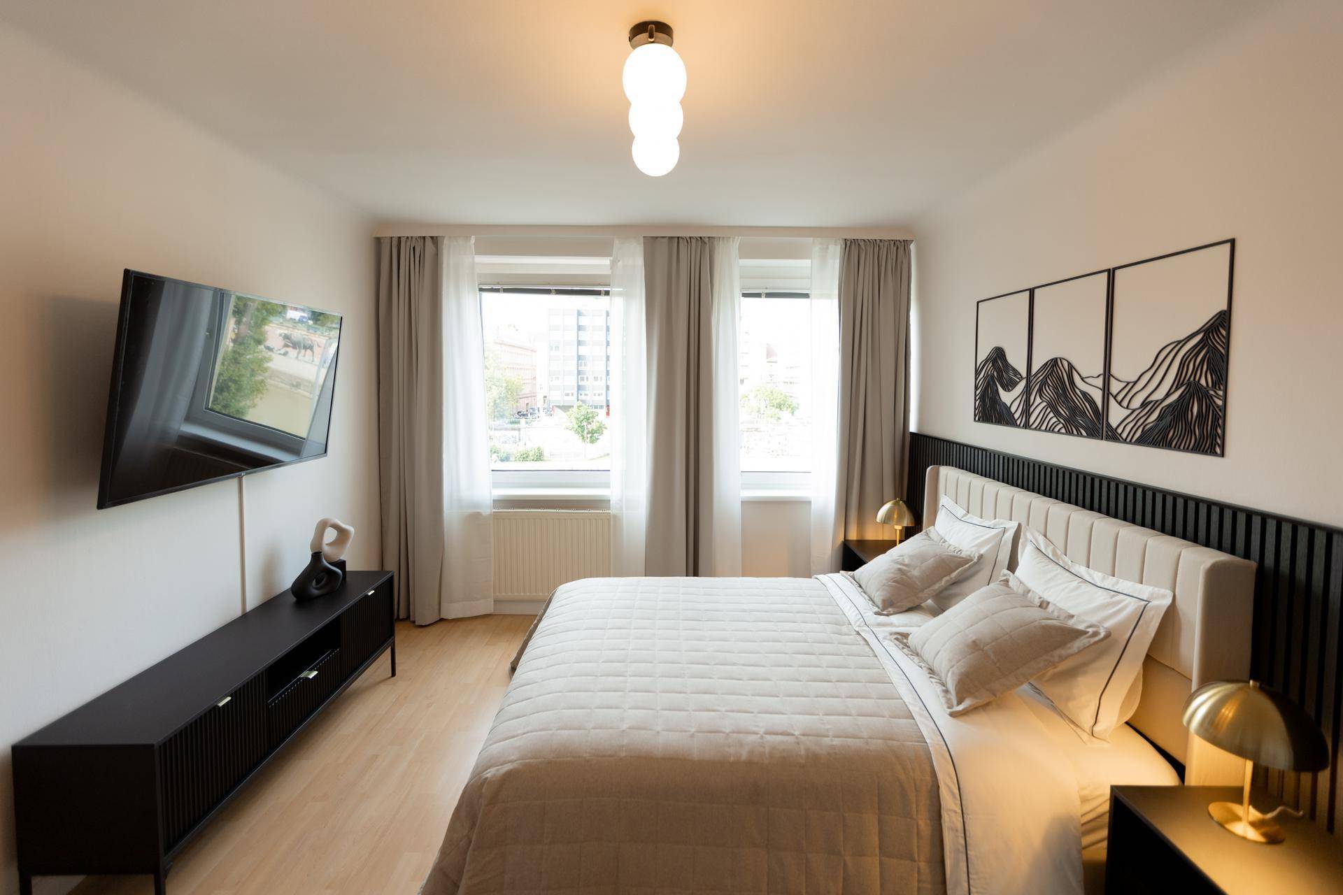 Geräumiges Schlafzimmer mit großem Bett, Wandfernseher und moderner Dekoration.