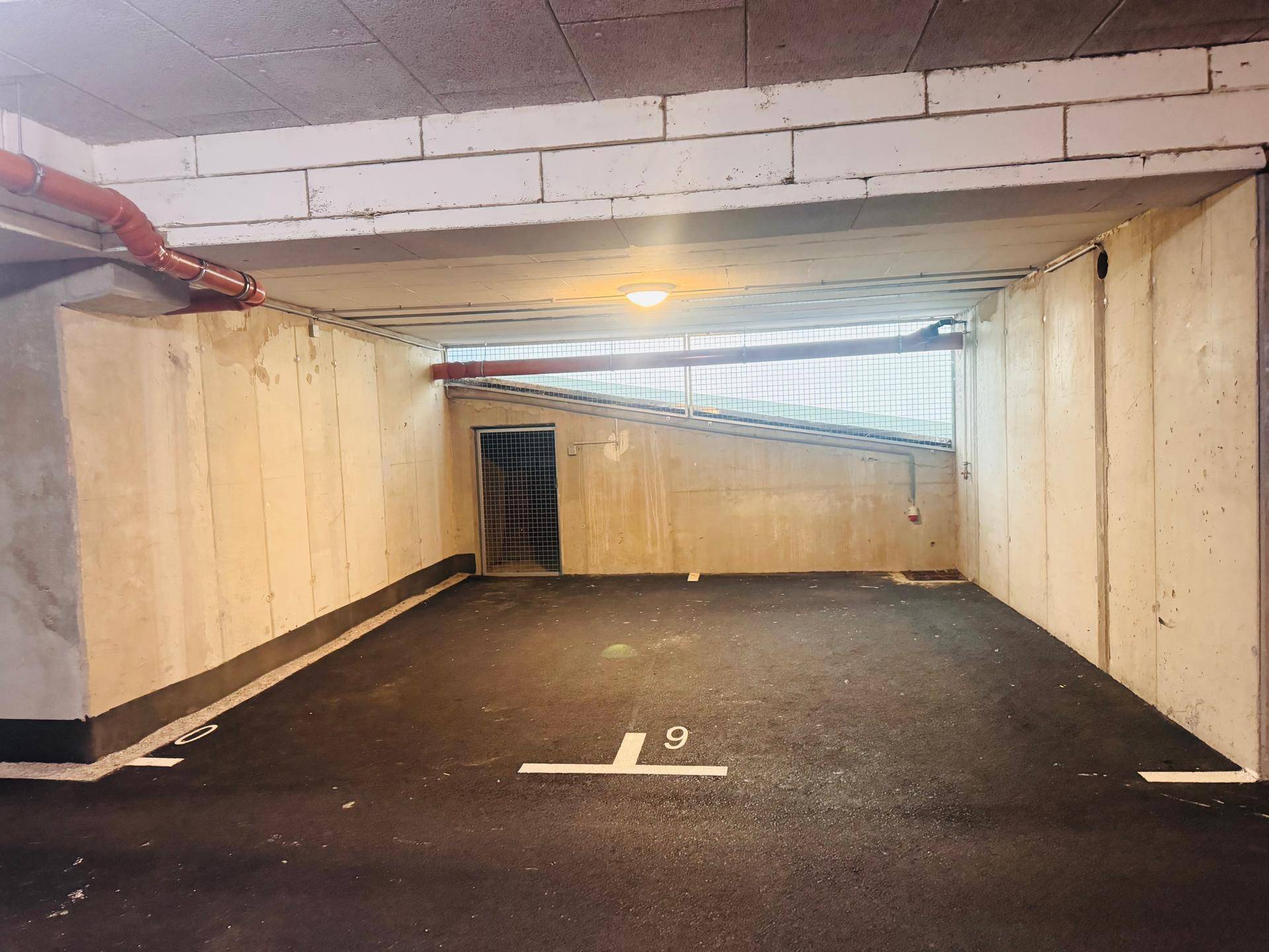 Geräumige Tiefgarage mit mehreren markierten Parkplätzen und Betonwänden.