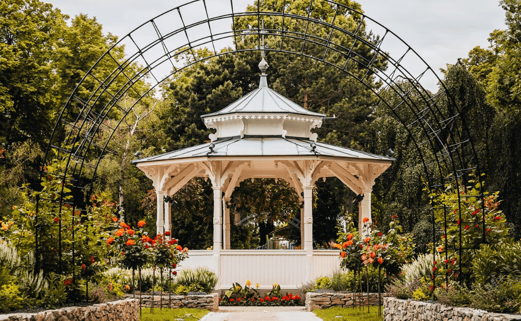 Malerischer Garten mit einem weißen Pavillon und Rosenbögen, eine idyllische Oase.
