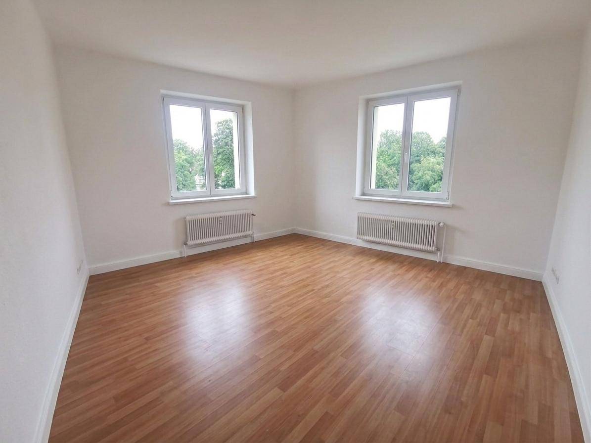 Geräumiges, leeres Schlafzimmer mit Holzboden und zwei Fenstern, bietet viel Gestaltungspotenzial.