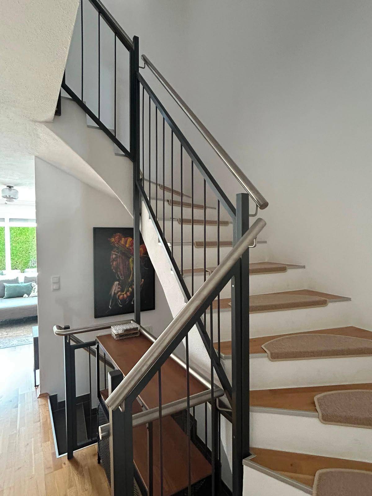 Moderne Treppe mit Holzstufen und Metallgeländer, die die verschiedenen Ebenen verbindet.