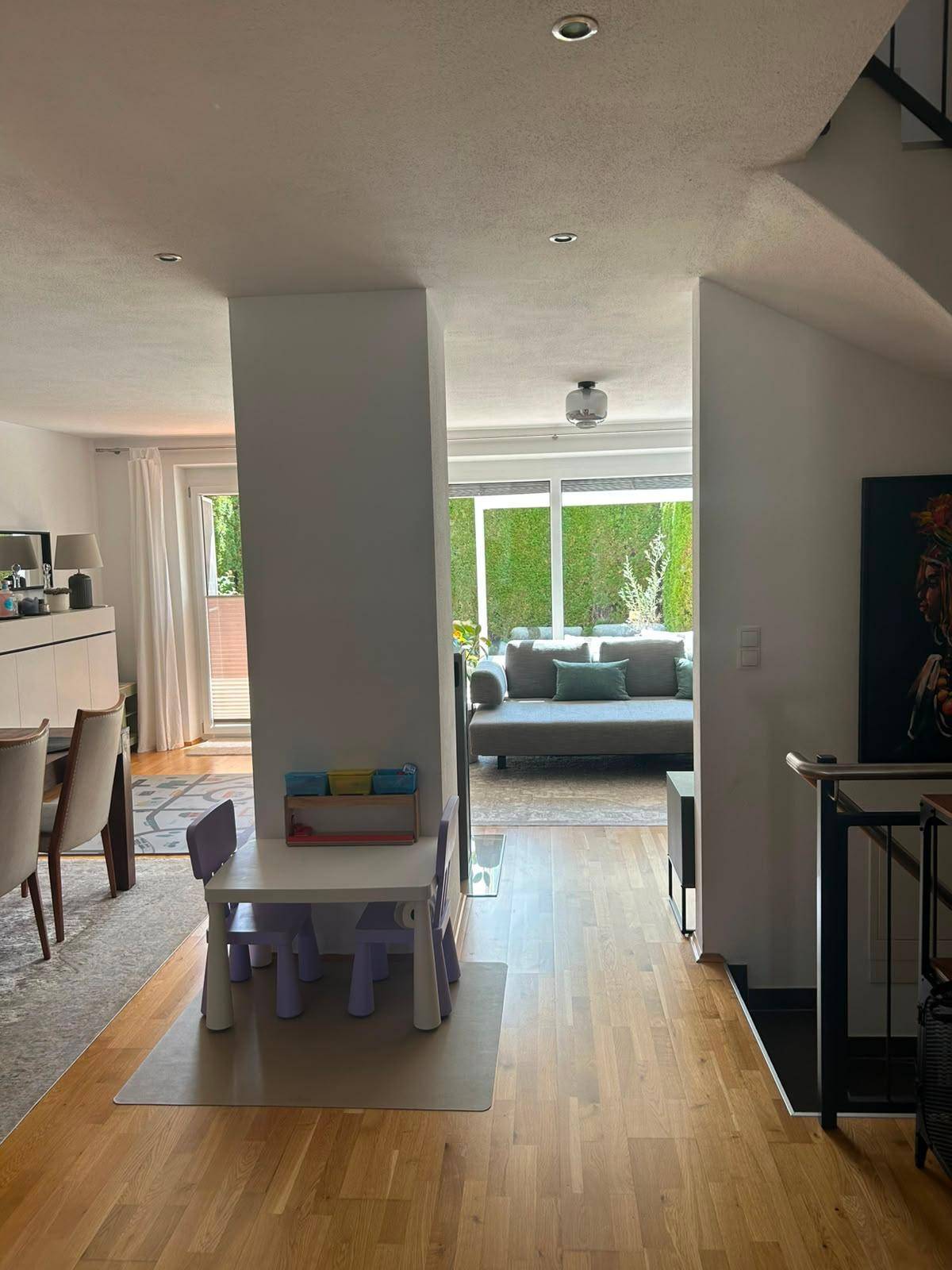 Offener Wohnbereich mit Kinderspielecke und Blick auf den hellen Wohnraum mit Zugang zum Garten.