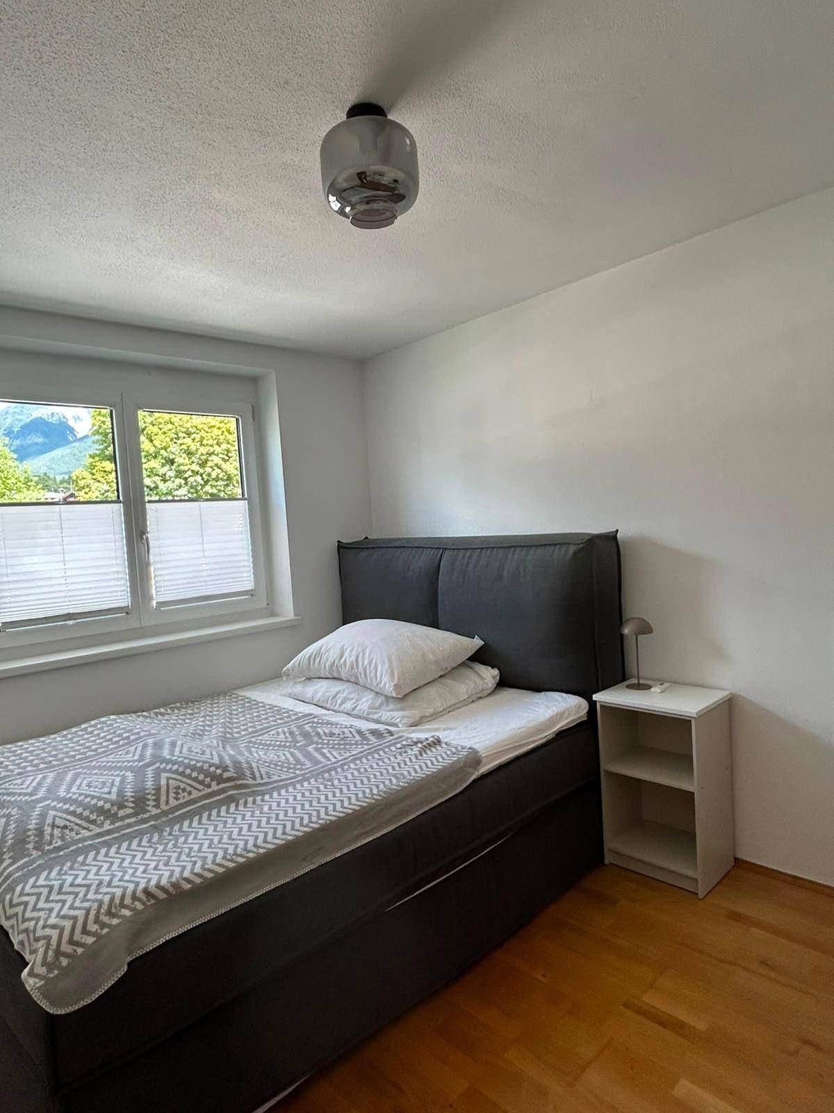 Schlafzimmer mit Doppelbett, Holzboden und Fenster mit Blick auf die Berge.