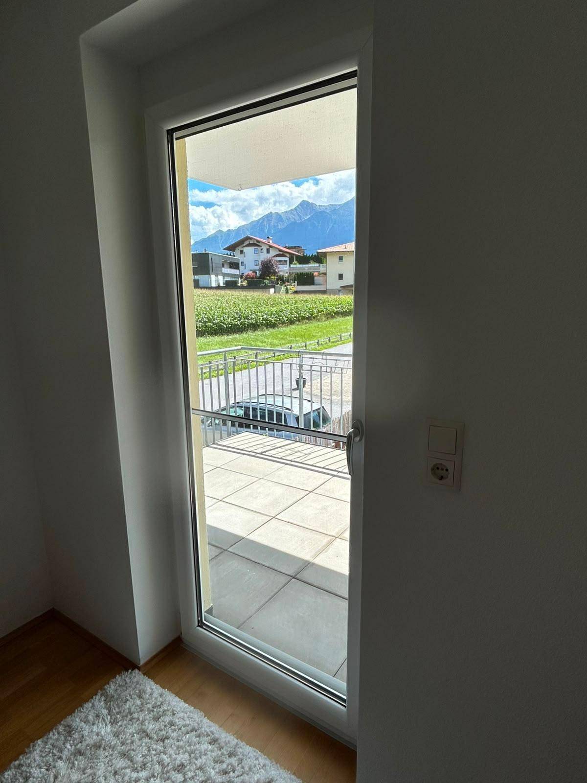 Balkontür im Schlafzimmer mit weitem Blick auf die Berge und die grüne Landschaft.