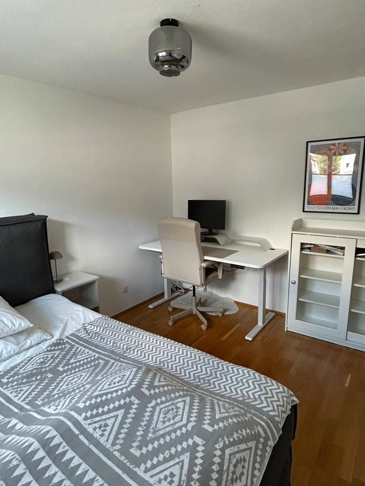 Helles Schlafzimmer mit Doppelbett, Schreibtisch und Blick auf die umliegende Landschaft.