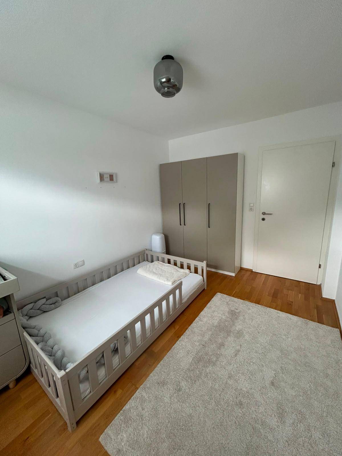 Kinderzimmer mit Holzboden, modernem Kleiderschrank und viel Tageslicht.