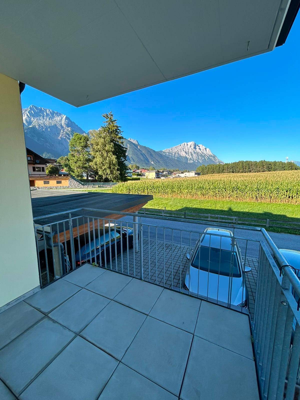 Panoramablick vom Balkon auf die beeindruckende Bergwelt und ein grünes Feld in der Ferne.