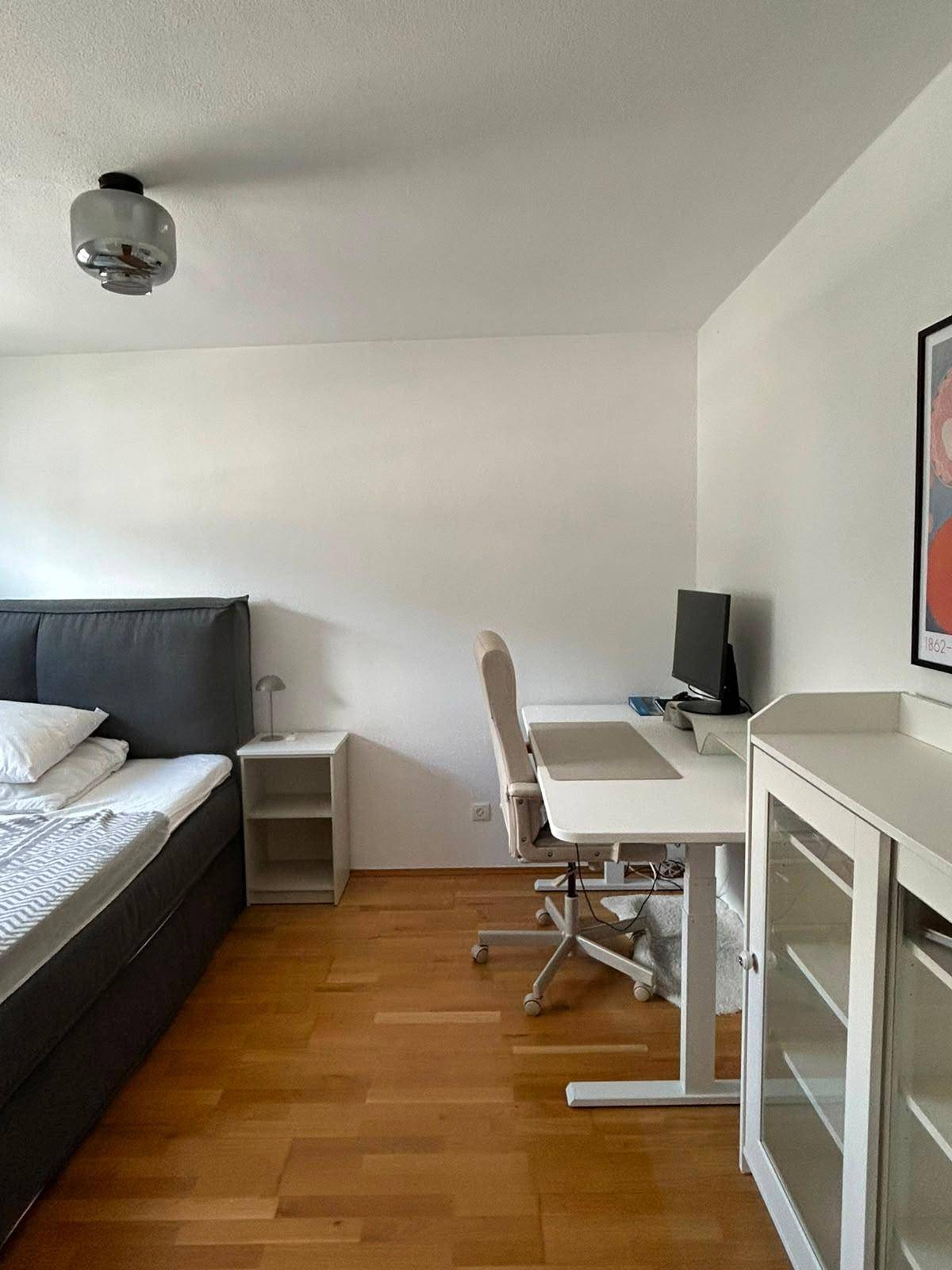 Schlafzimmer mit Doppelbett, Schreibtisch und Holzboden, ideal als Home-Office.