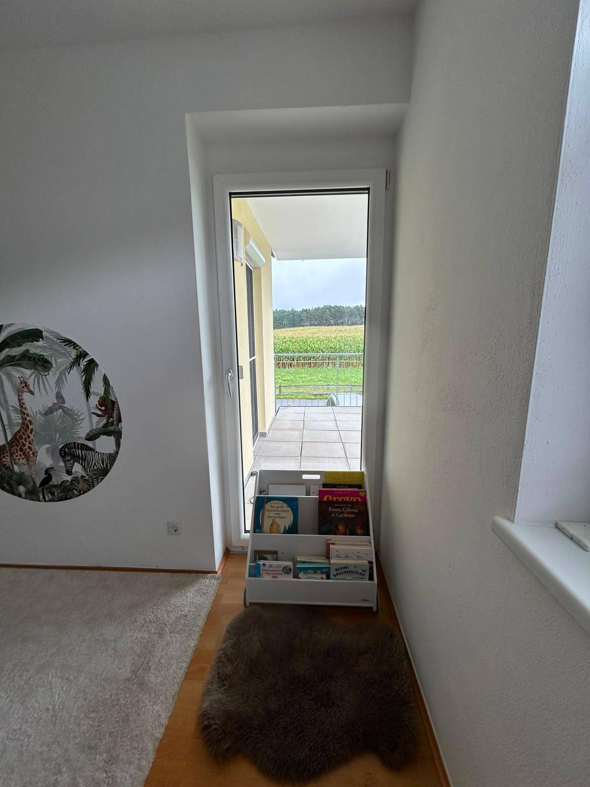 Kinderzimmer mit Zugang zu einem Balkon oder einer Terrasse und weitem Blick in die Landschaft.