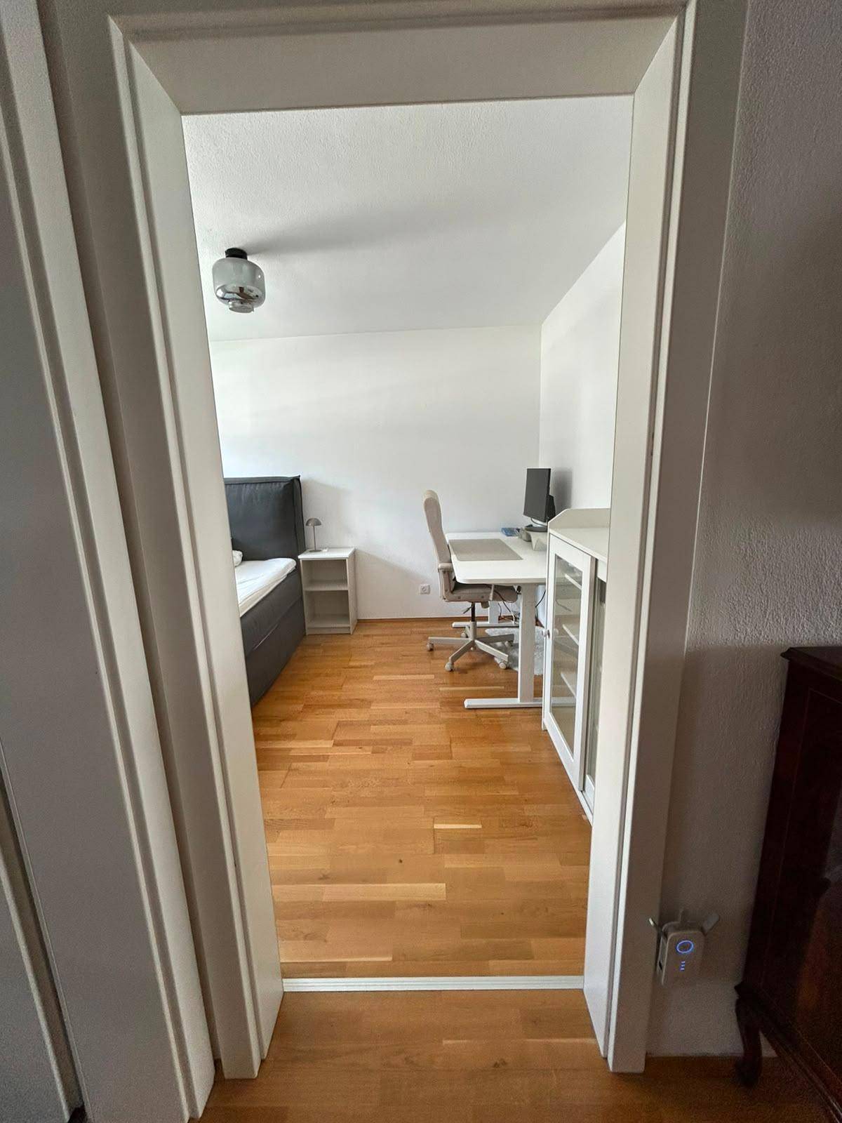 Blick in ein helles Schlafzimmer mit Holzboden und modernem Mobiliar.