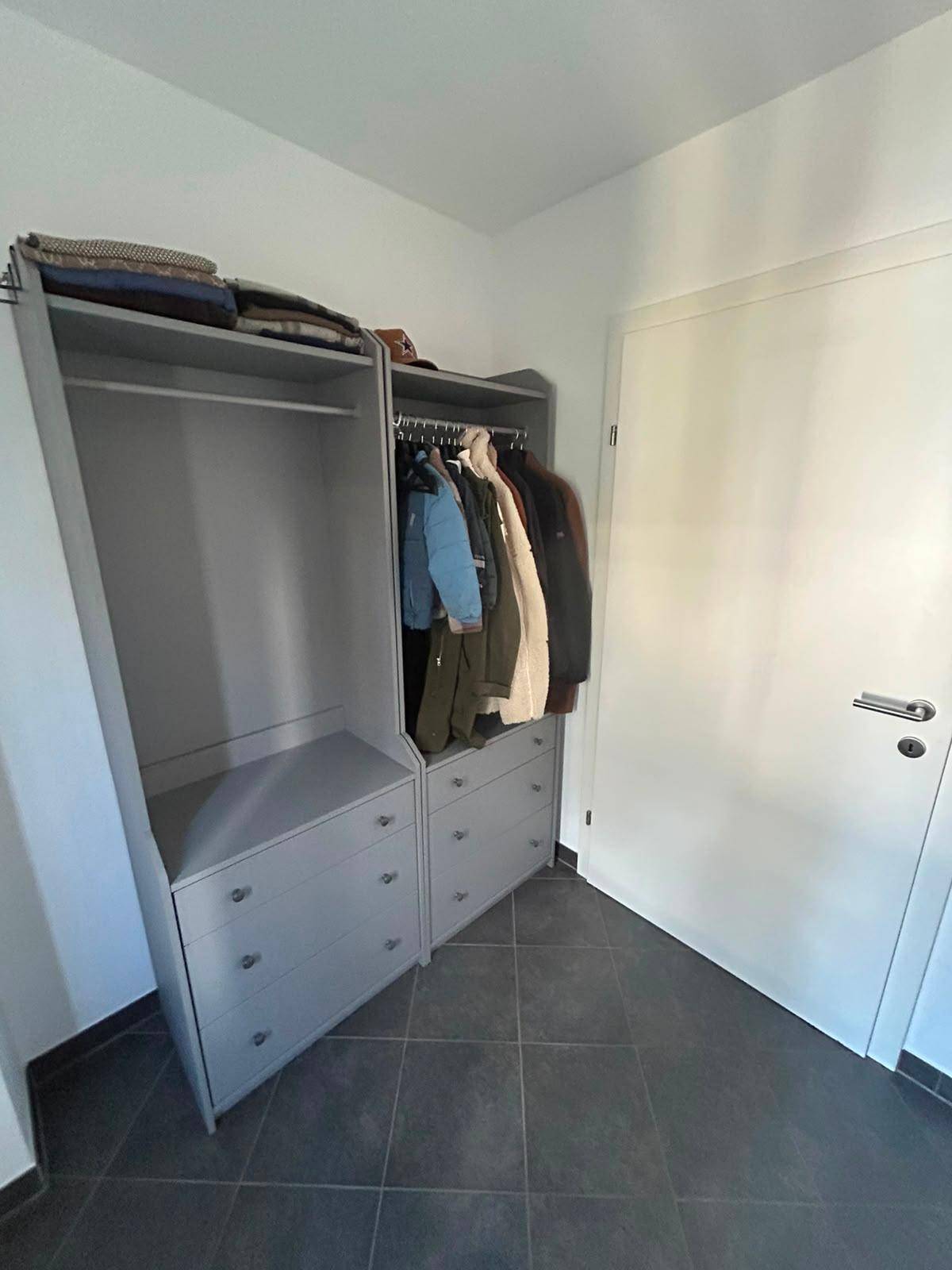 Flur mit praktischem Kleiderschrank und dunklen Bodenfliesen im Eingangsbereich.