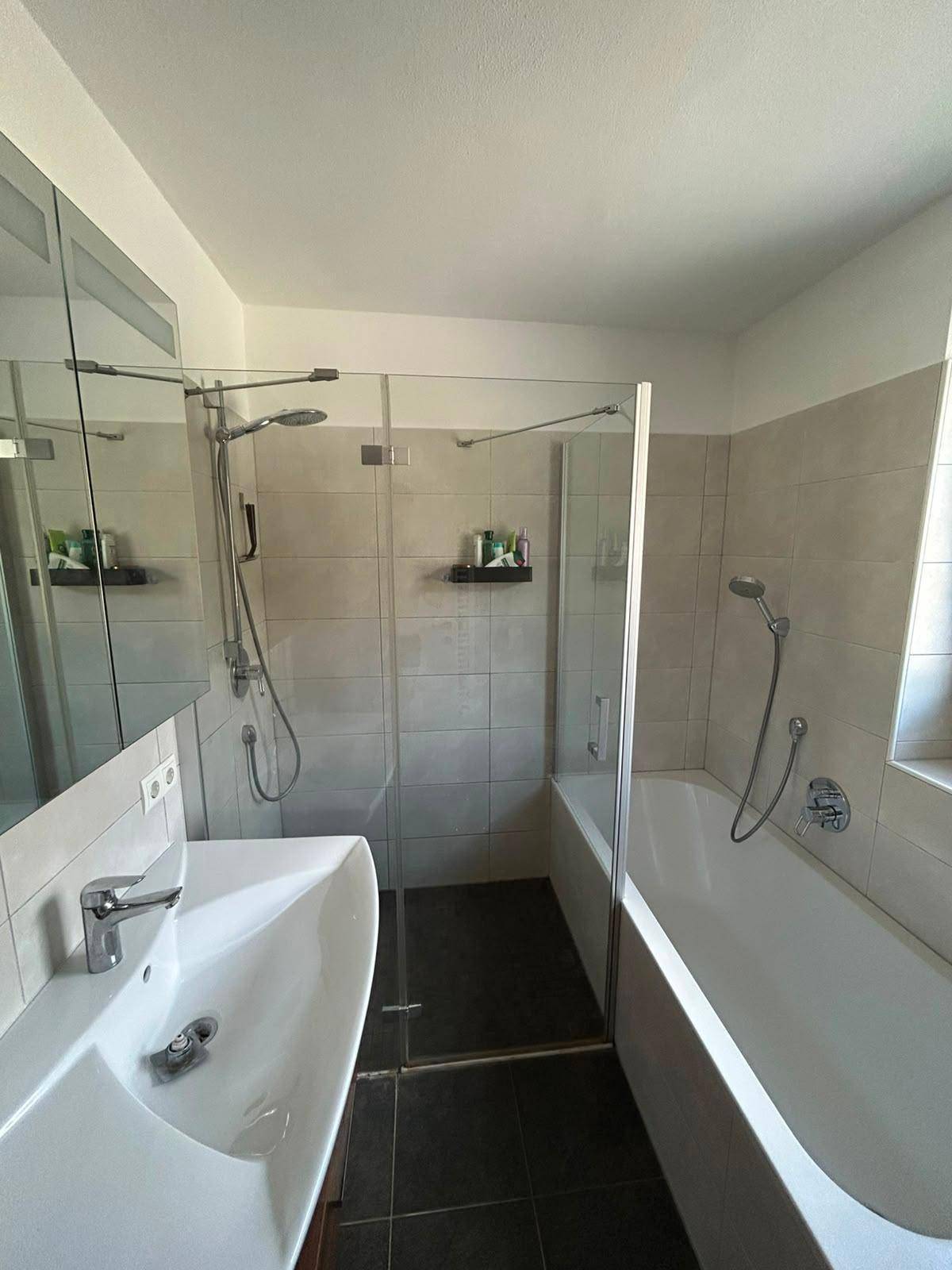 Badezimmer mit Badewanne, Duschabtrennung, modernem Waschbecken und Spiegelschrank.