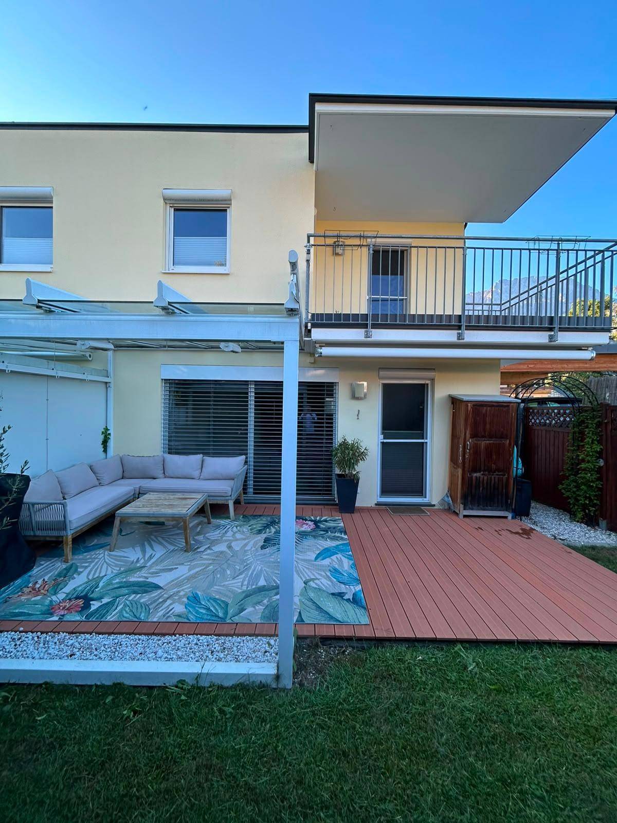 Geräumige Terrasse mit Holzdeck und gemütlicher Lounge-Ecke, angrenzend an einen gepflegten Garten.