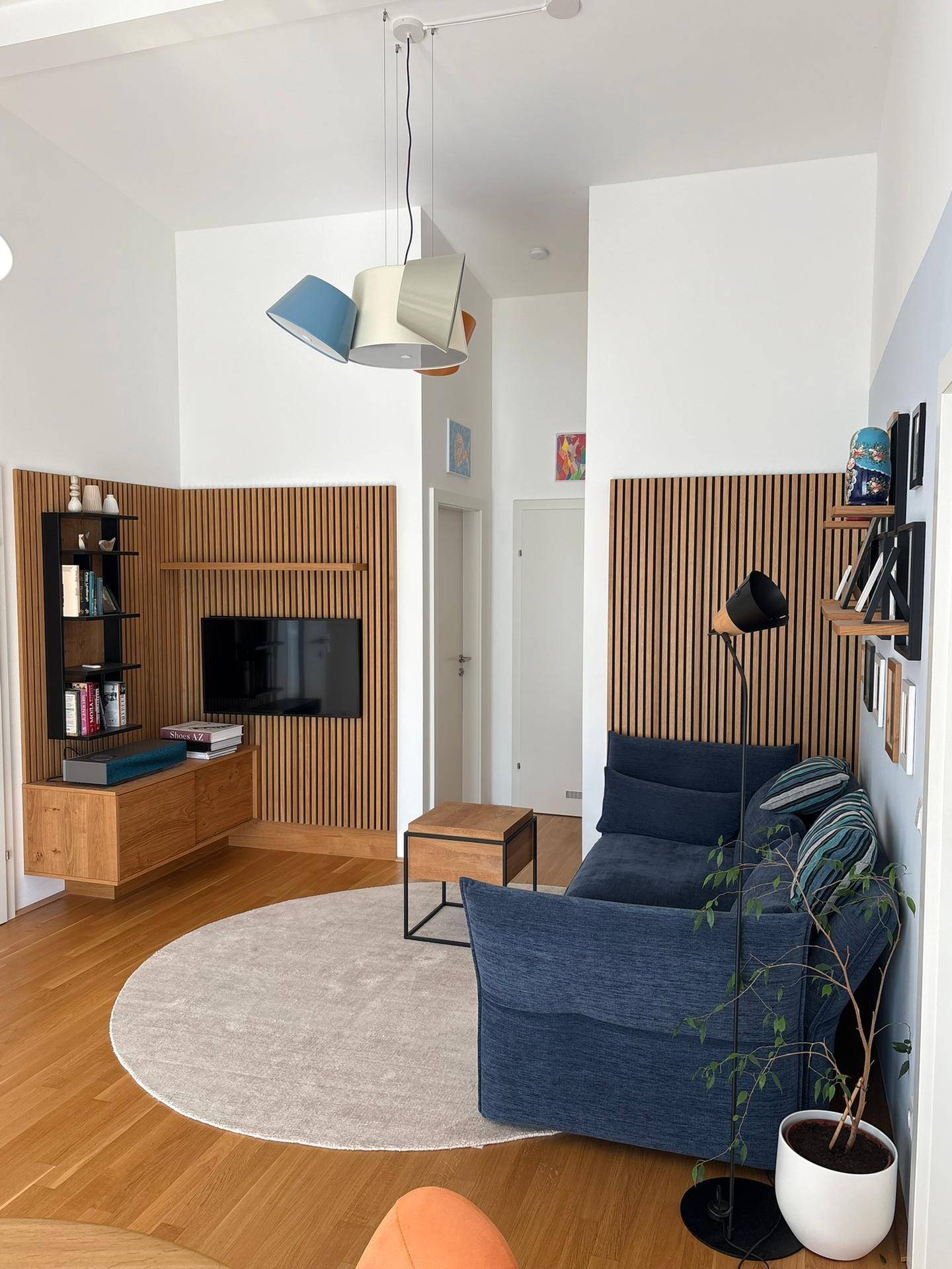 Modernes Wohnzimmer mit Holzakzenten, bequemer Couch und stilvoller Beleuchtung in hellem Ambiente.