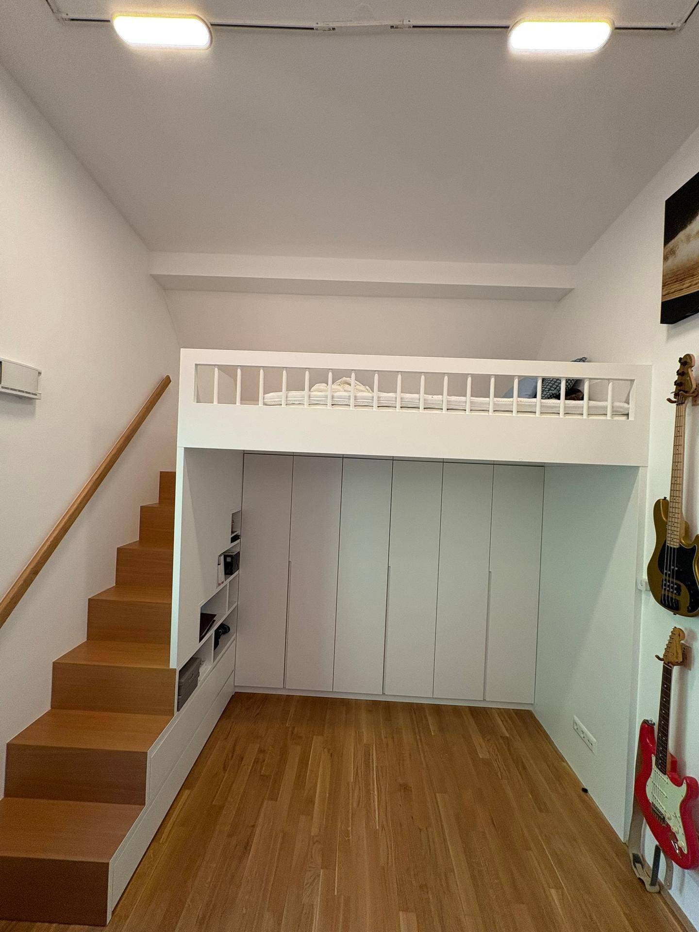 Helles Kinderzimmer mit Hochbett, darunterliegenden Schränken und Holztreppe in modernem Design.