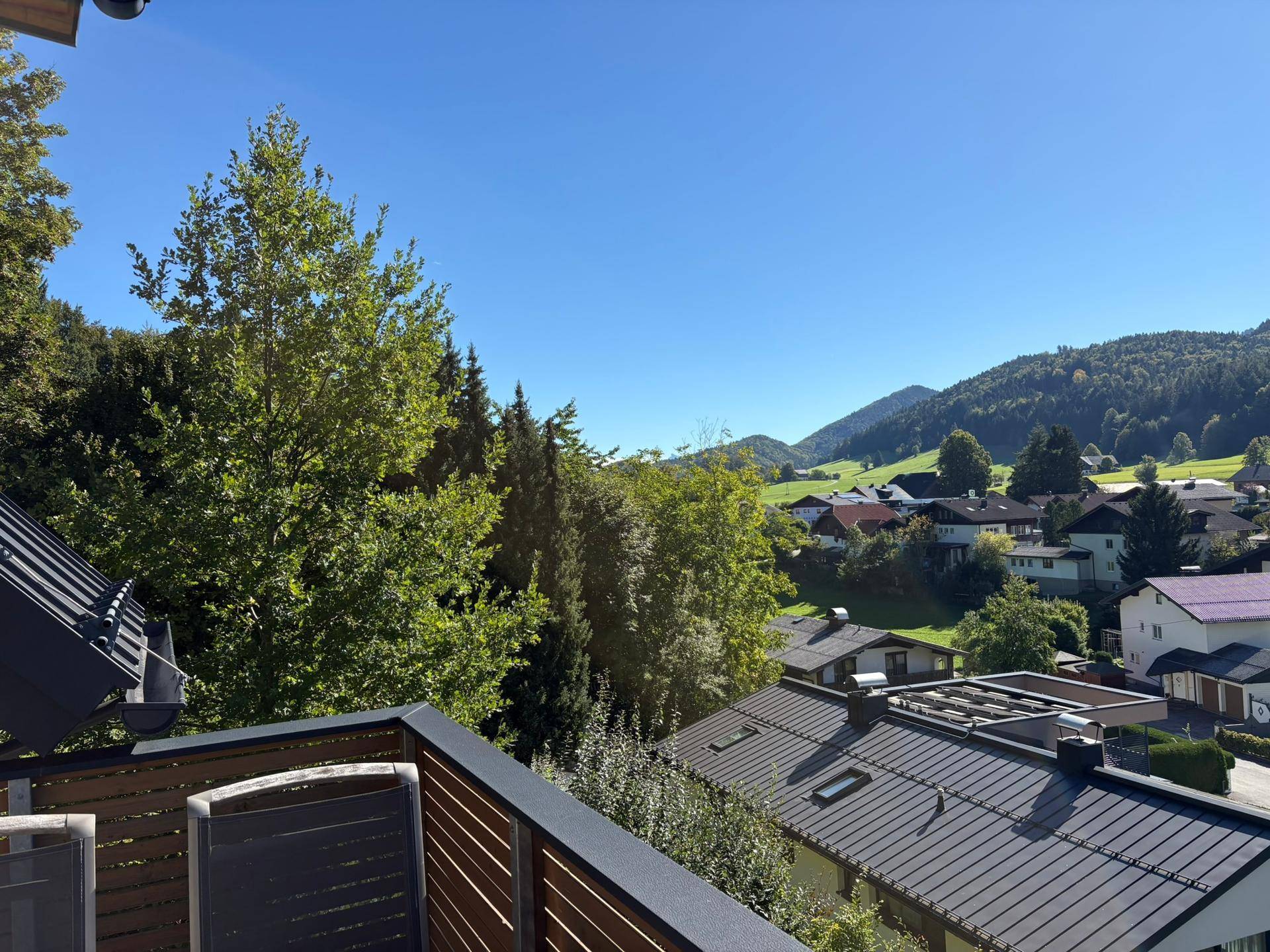 Balkon mit Blick auf die bewaldeten Hügel und die Dächer der umliegenden Häuser in der Natur.