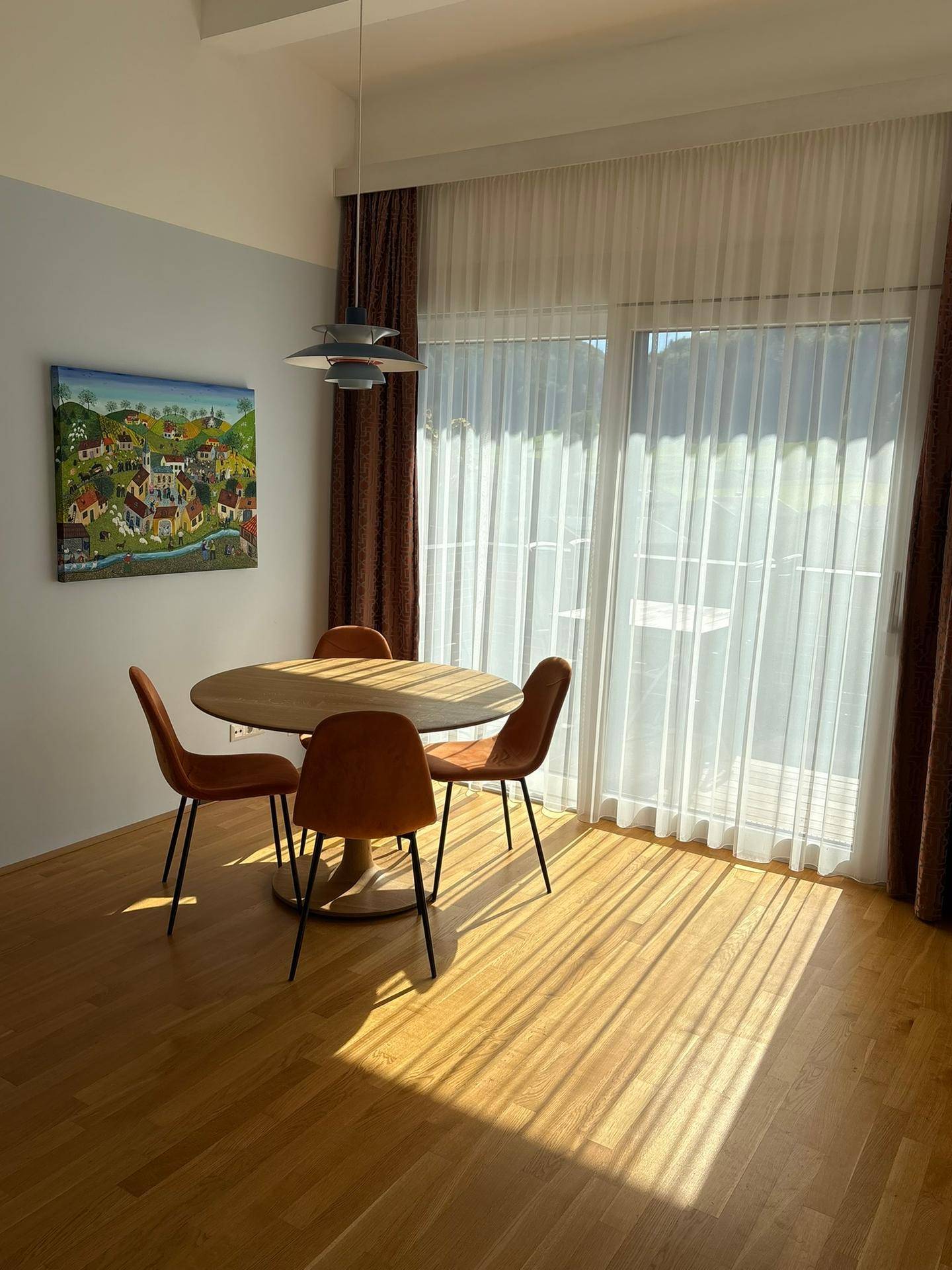 Lichtdurchfluteter Essbereich mit Holzboden und großem Fenster, das viel Tageslicht hereinlässt.
