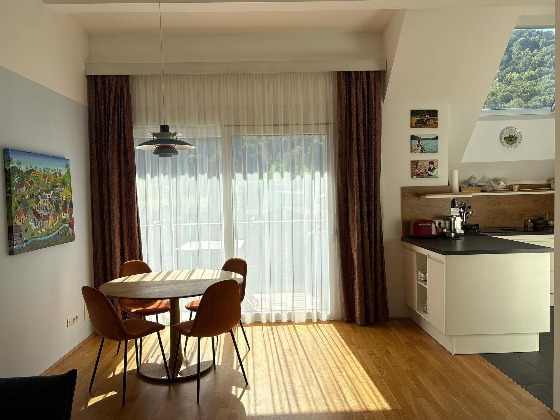 Heller Essbereich mit Holztisch und Stühlen, angrenzend an eine moderne Küche mit Balkonzugang.