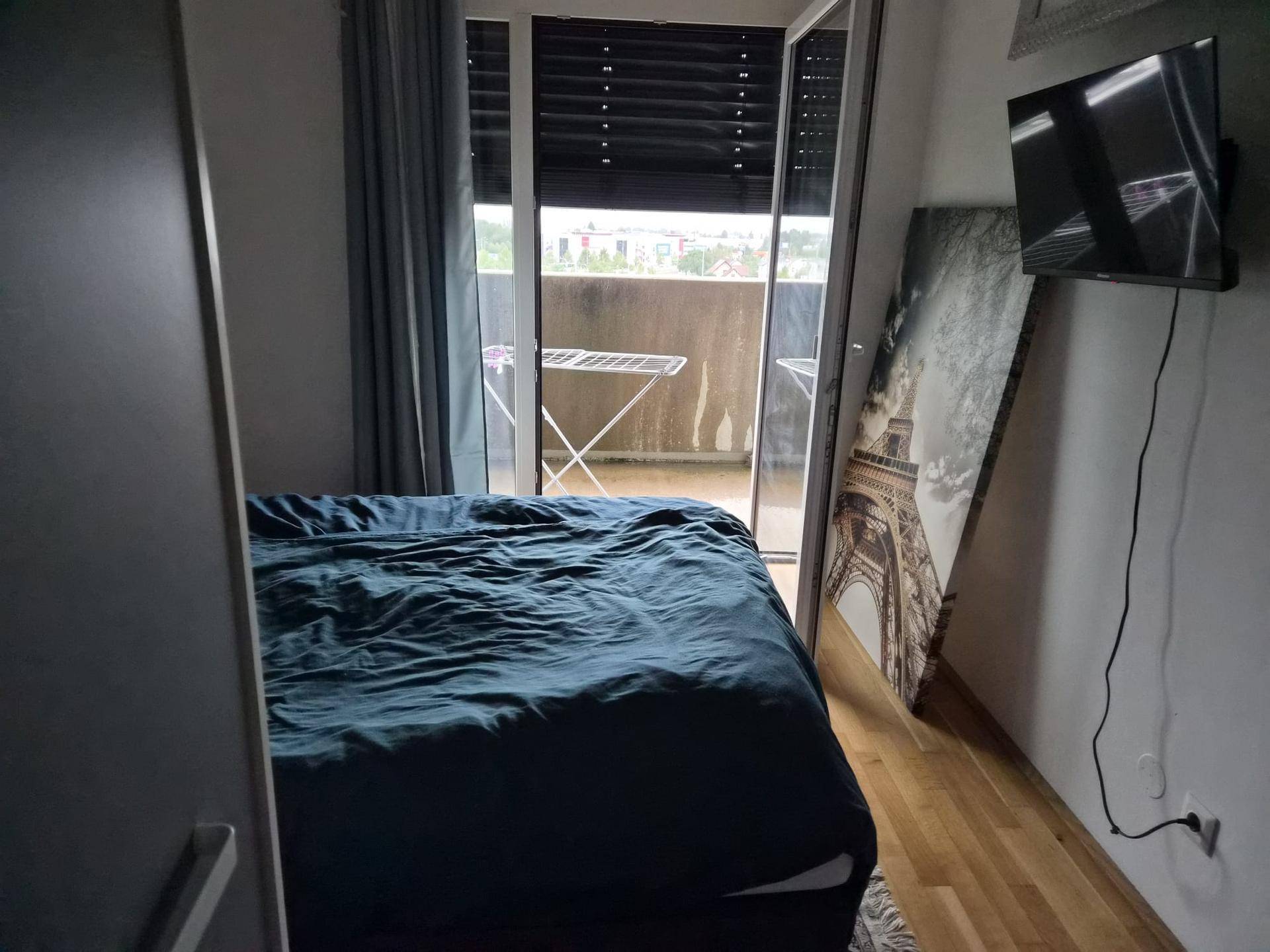 Schlafzimmer mit Doppelbett, Balkonzugang und Blick auf den Außenbereich.