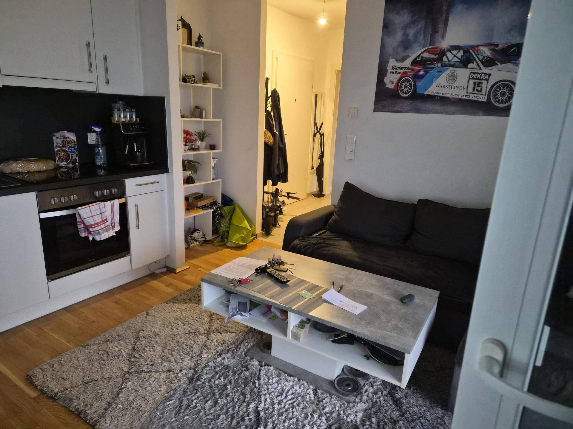 Offener Wohnbereich mit kleiner Küchenzeile, Sofa und modernem Couchtisch.