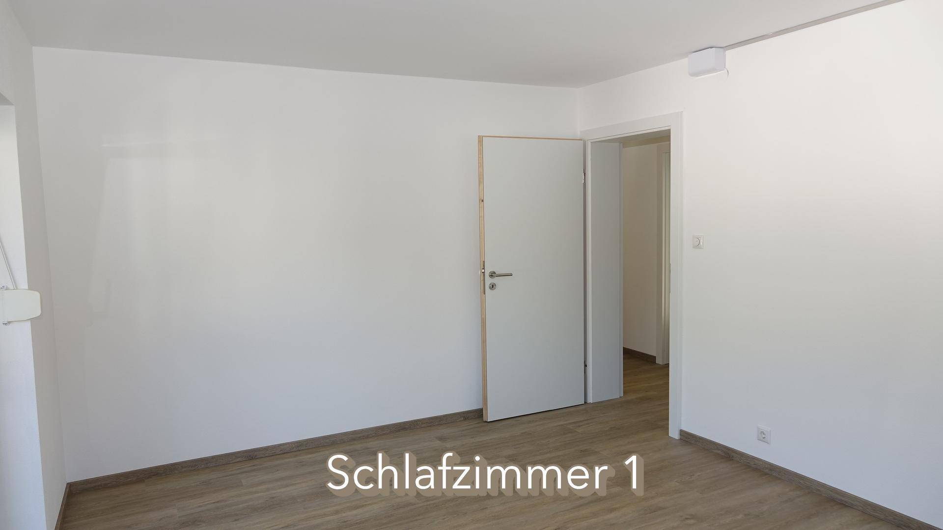 Schlafzimmer mit Laminatboden und weiß gestrichenen Wänden, bereit zur individuellen Gestaltung.