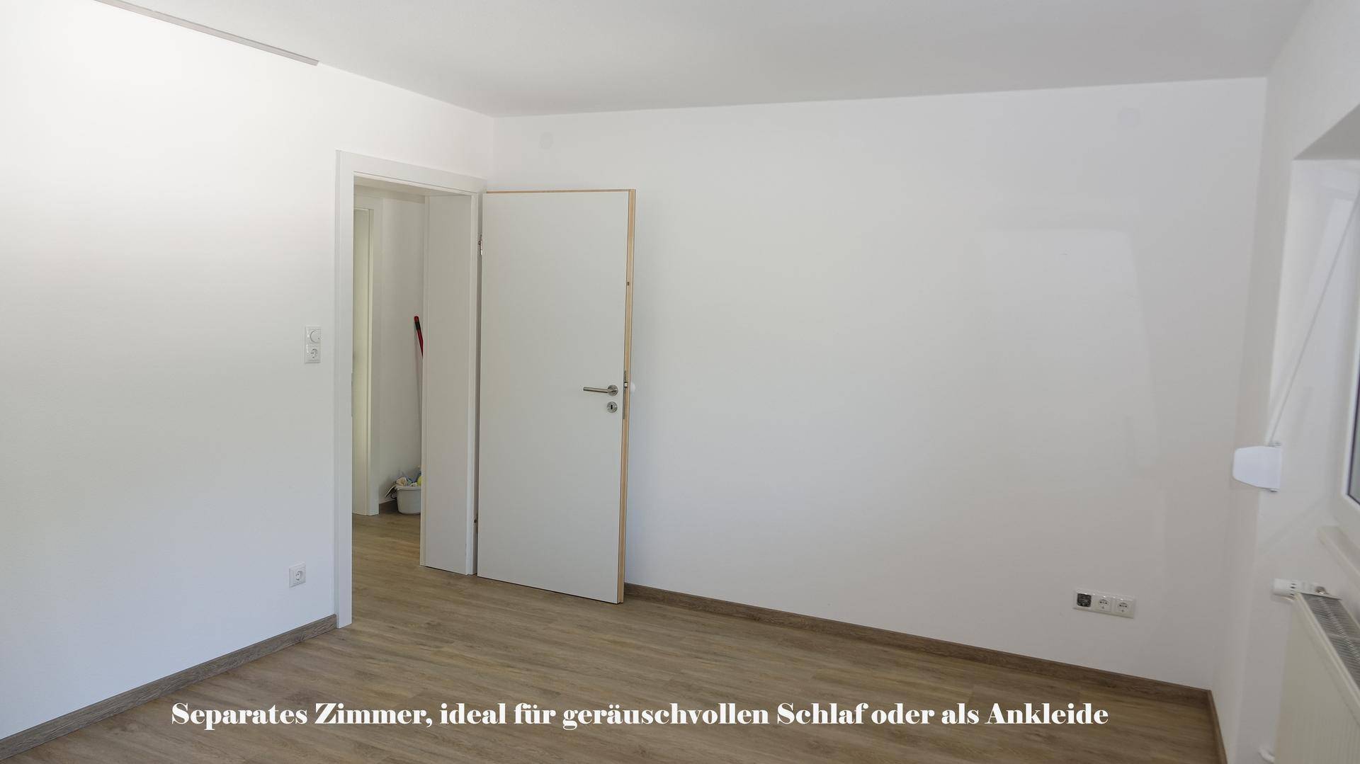 Separates Zimmer mit Laminatboden und weißen Wänden, ideal als ruhiges Schlafzimmer oder Ankleidebereich.