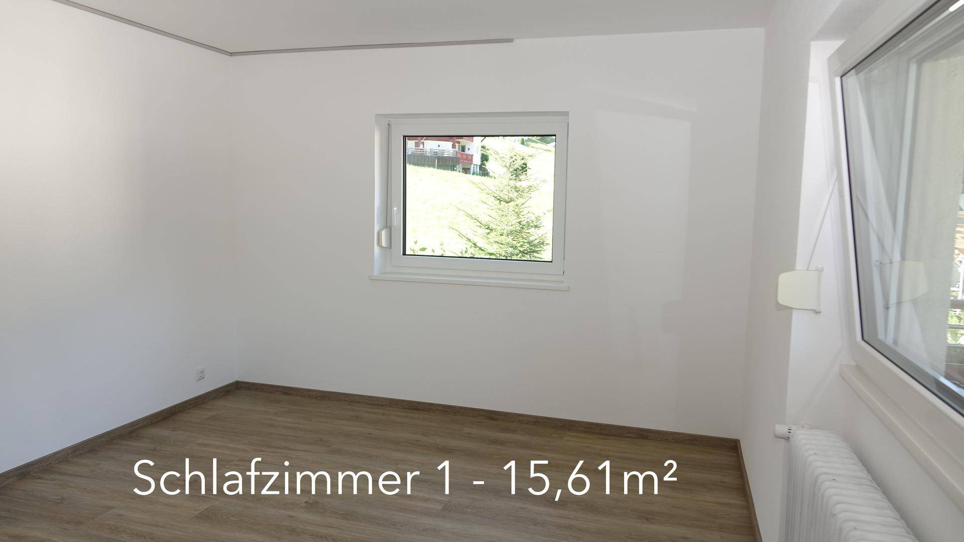 Geräumiges Schlafzimmer mit Laminatboden, weißen Wänden und Blick ins Grüne.